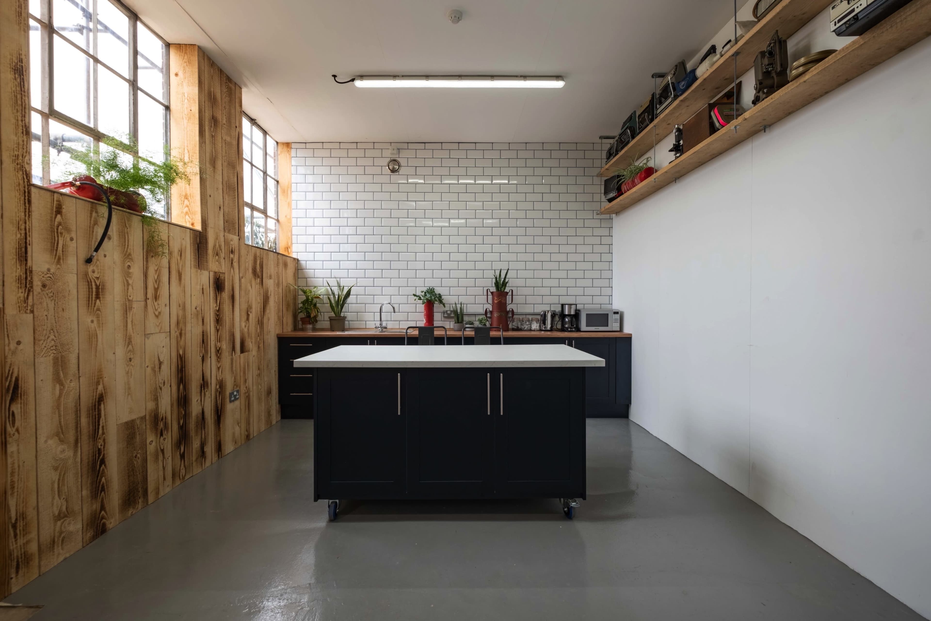 A modern kitchen features a central island, white subway tile backsplash, and wooden accents against a minimalist design.