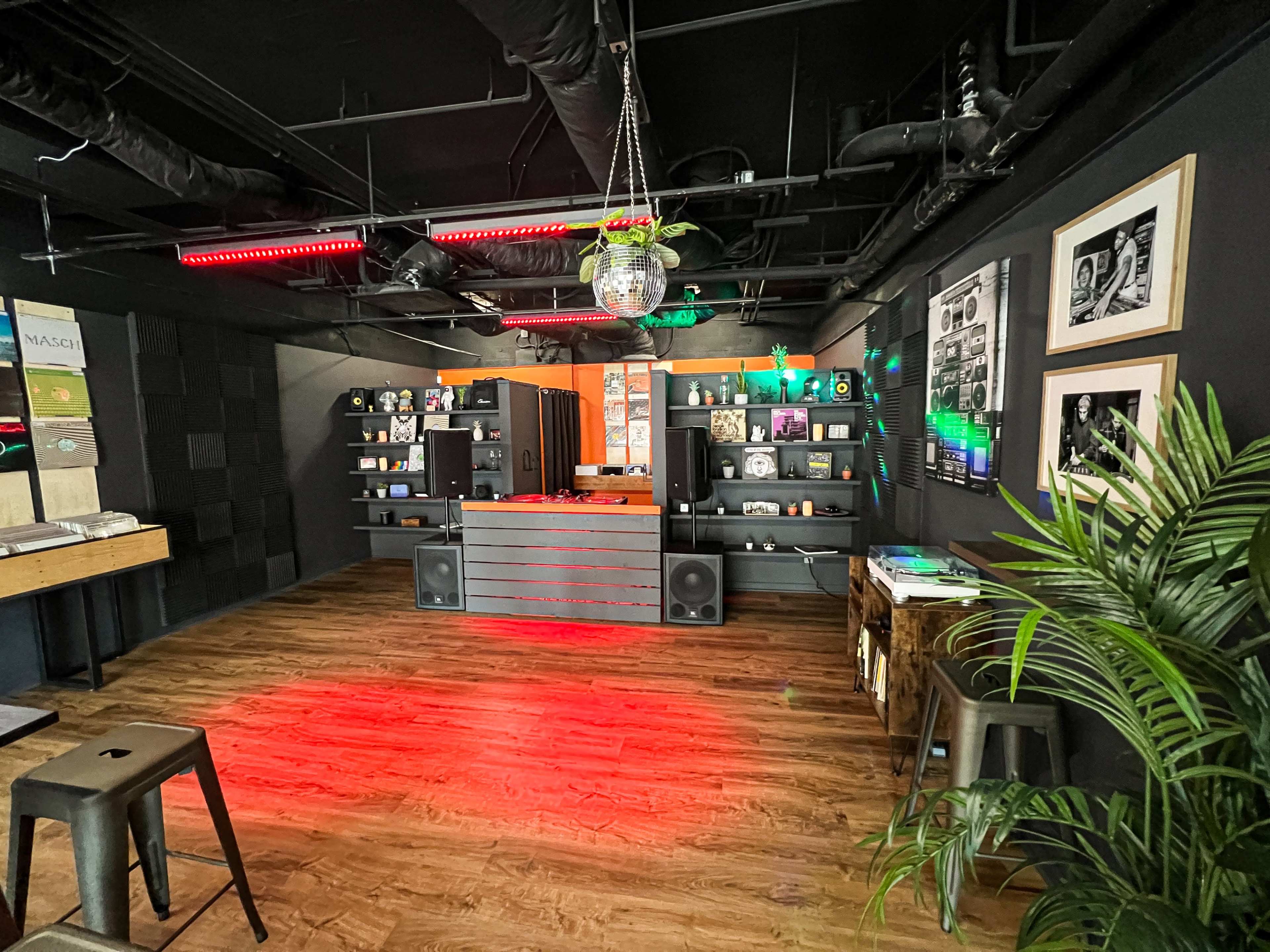 A modern music studio with a DJ setup, shelves of vinyl records, and disco lighting.