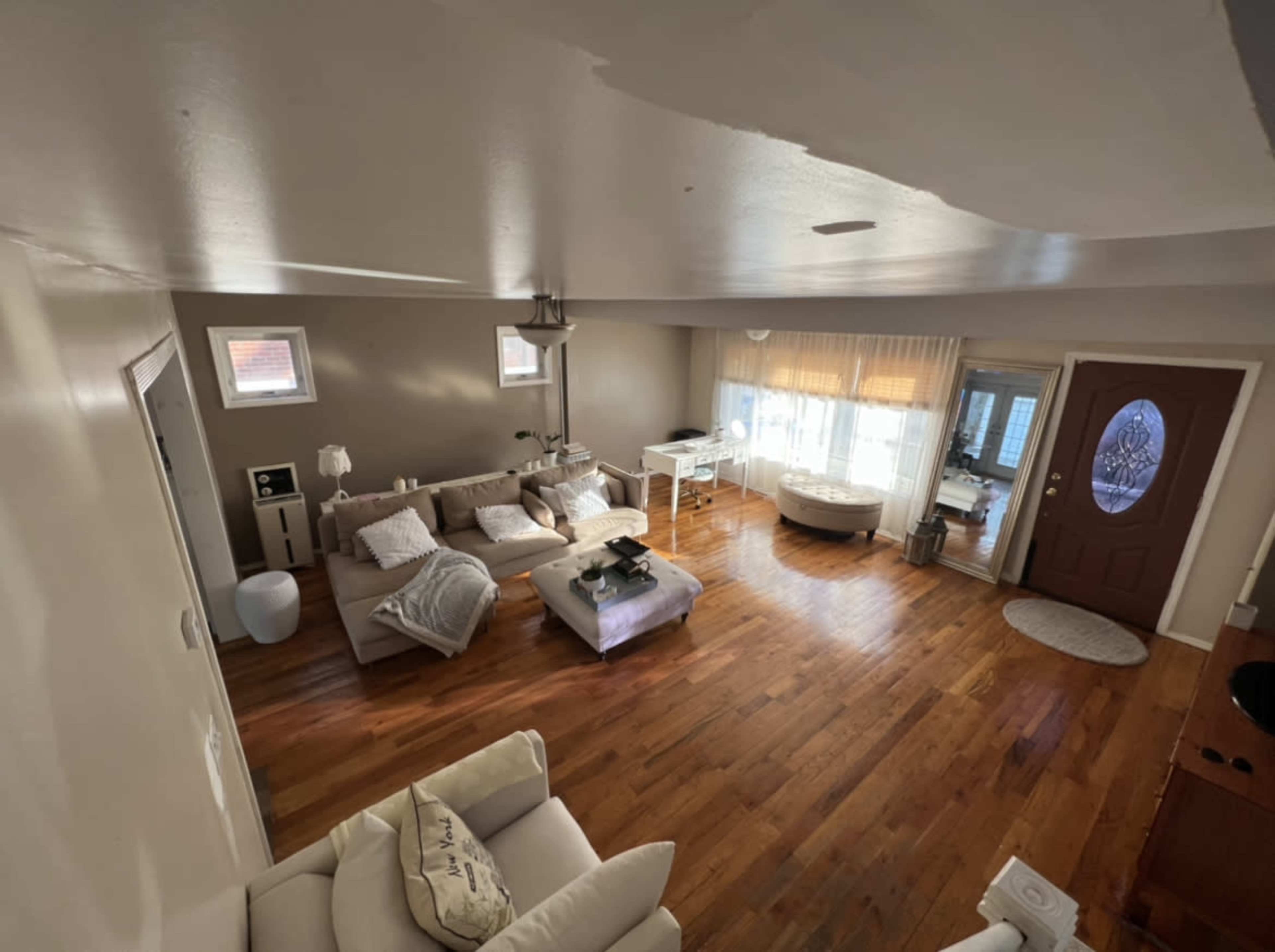 A spacious living room with hardwood flooring, a couch, coffee table, and a front door leading outside.