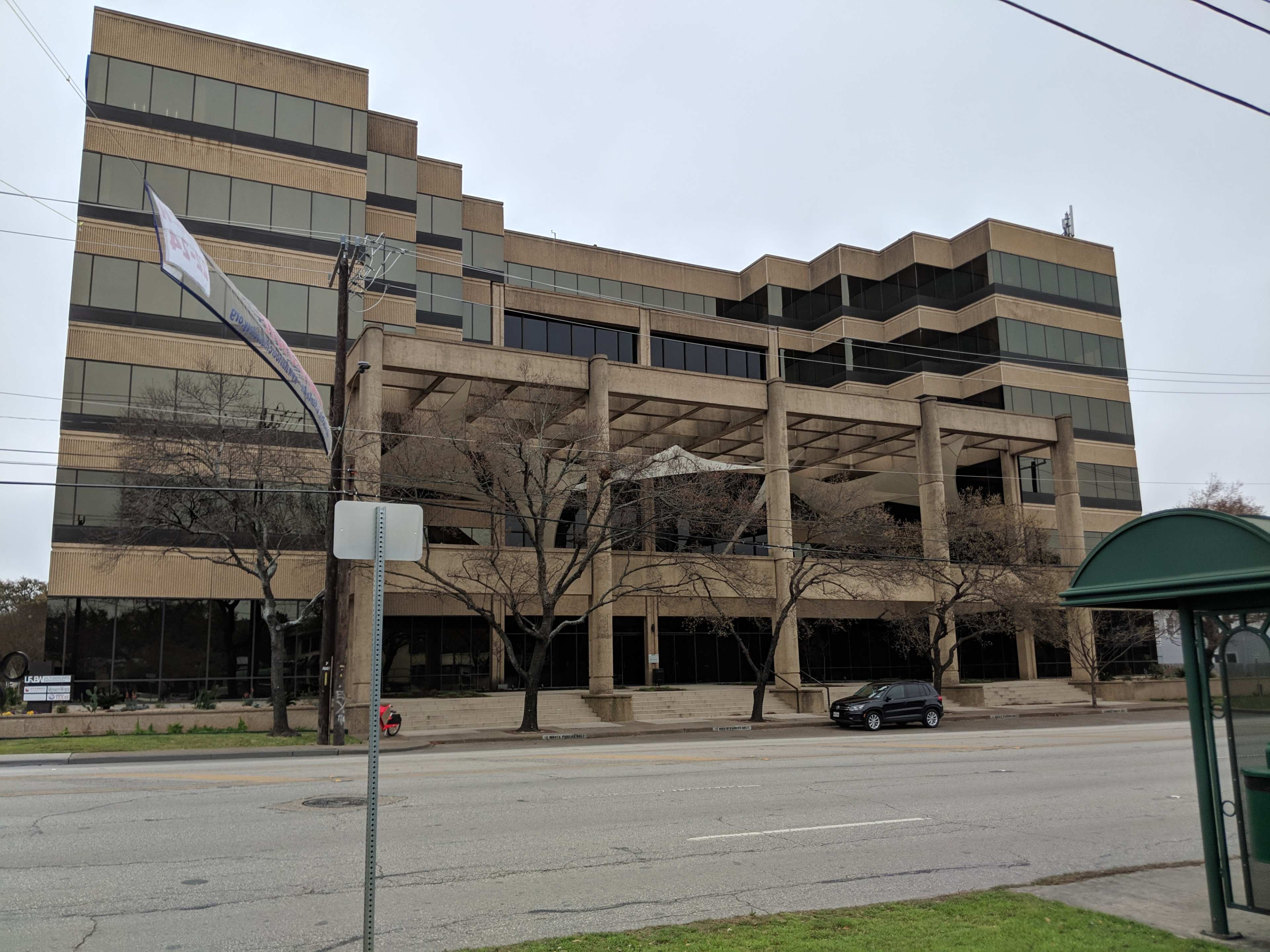 A large, five-story commercial building with a modern architectural design, featuring a concrete and glass facade and a covered entrance.