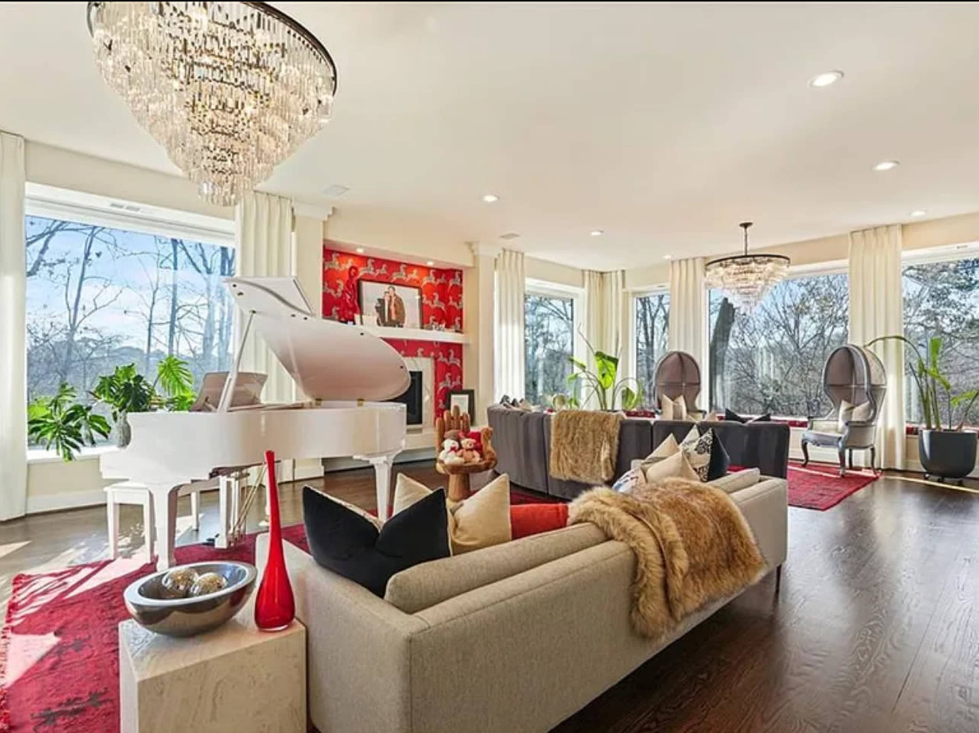 The image depicts a modern living room featuring a grand piano, large windows with natural light, and a mix of contemporary furniture and decor.
