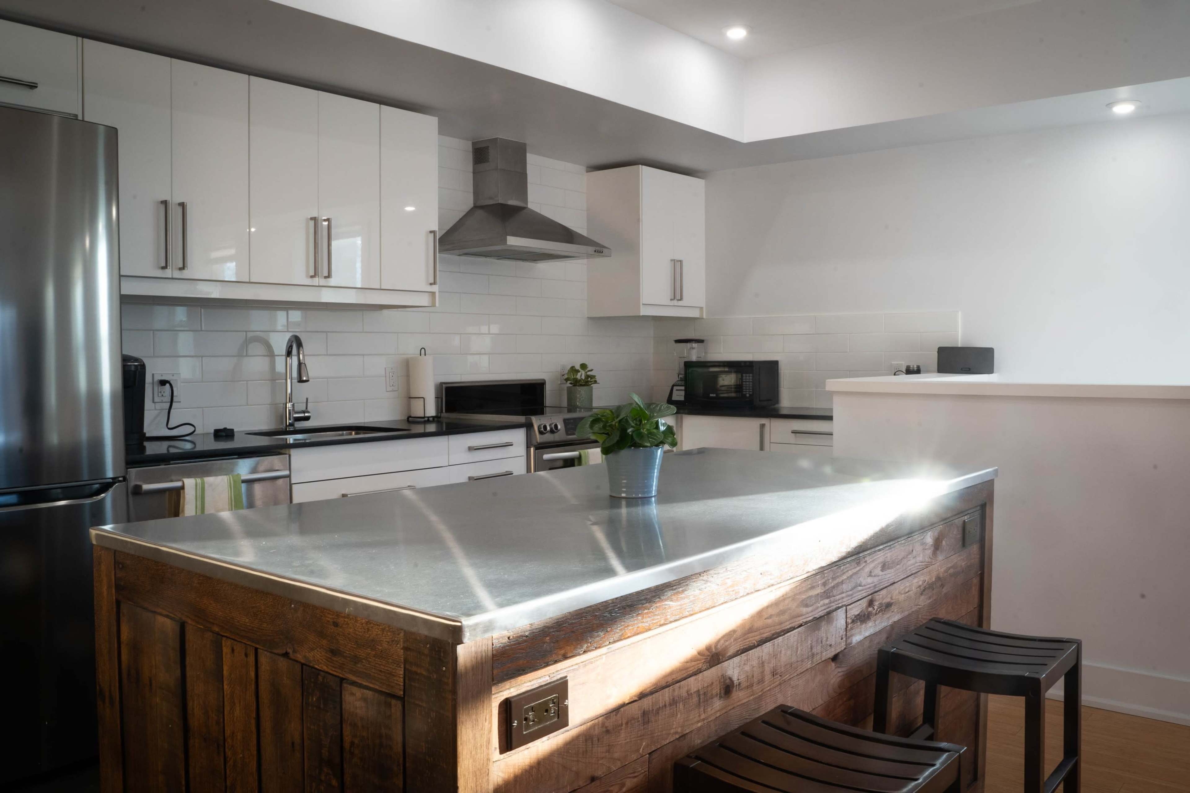 A modern kitchen with stainless steel appliances, a central wooden island, and white cabinetry.