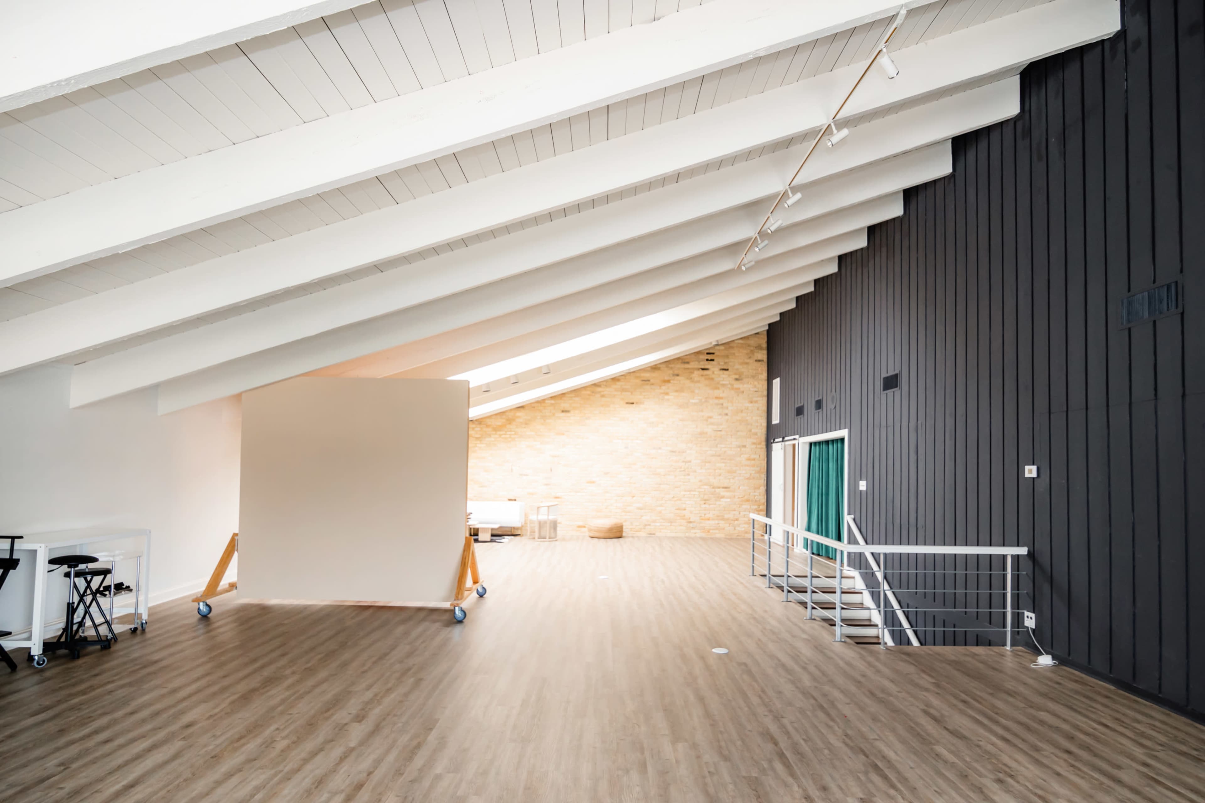 An interior space with high, sloped ceilings, wooden flooring, and contrasting light and dark wall sections.