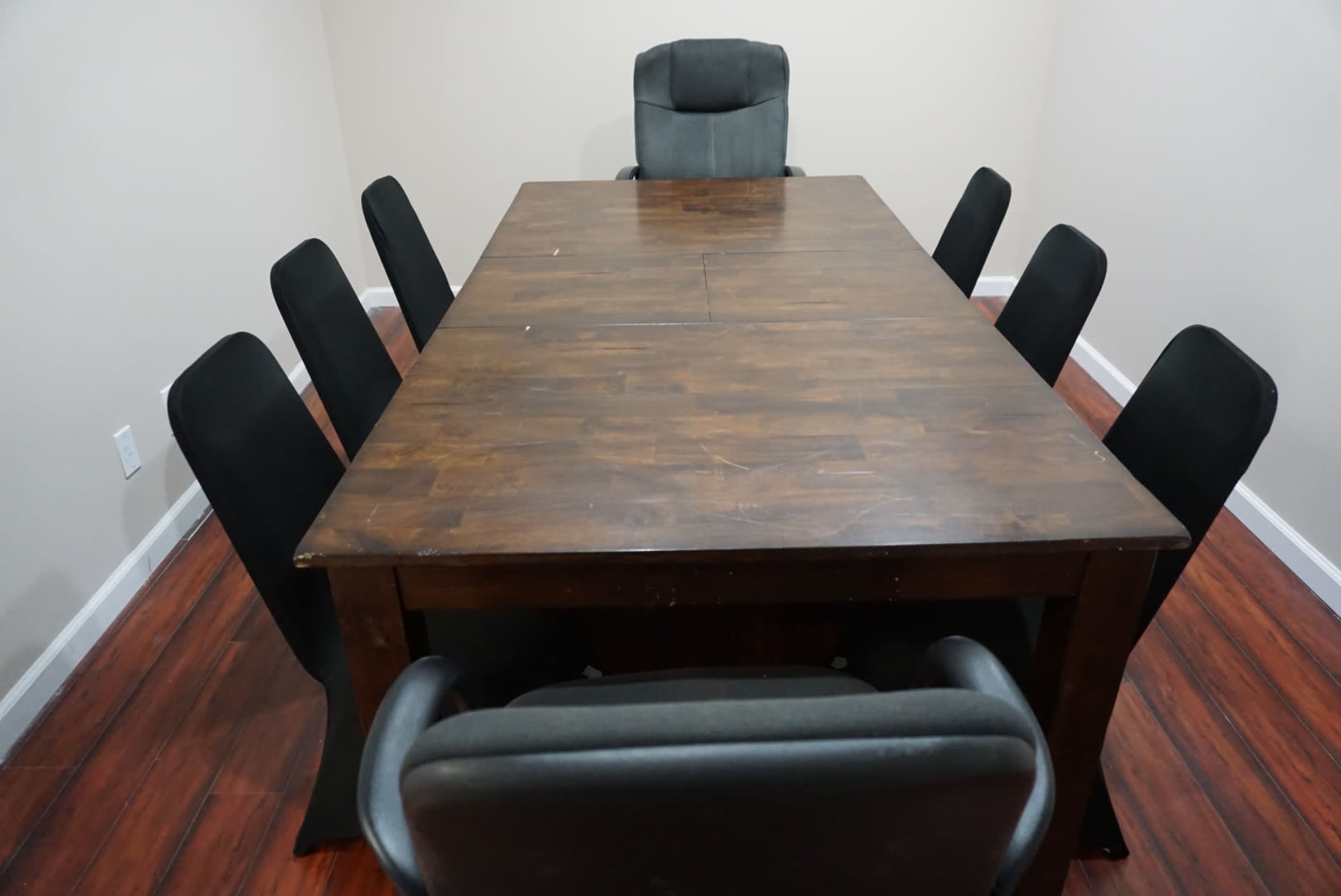 A large wooden conference table surrounded by eight black chairs, with an additional black chair at the head of the table.