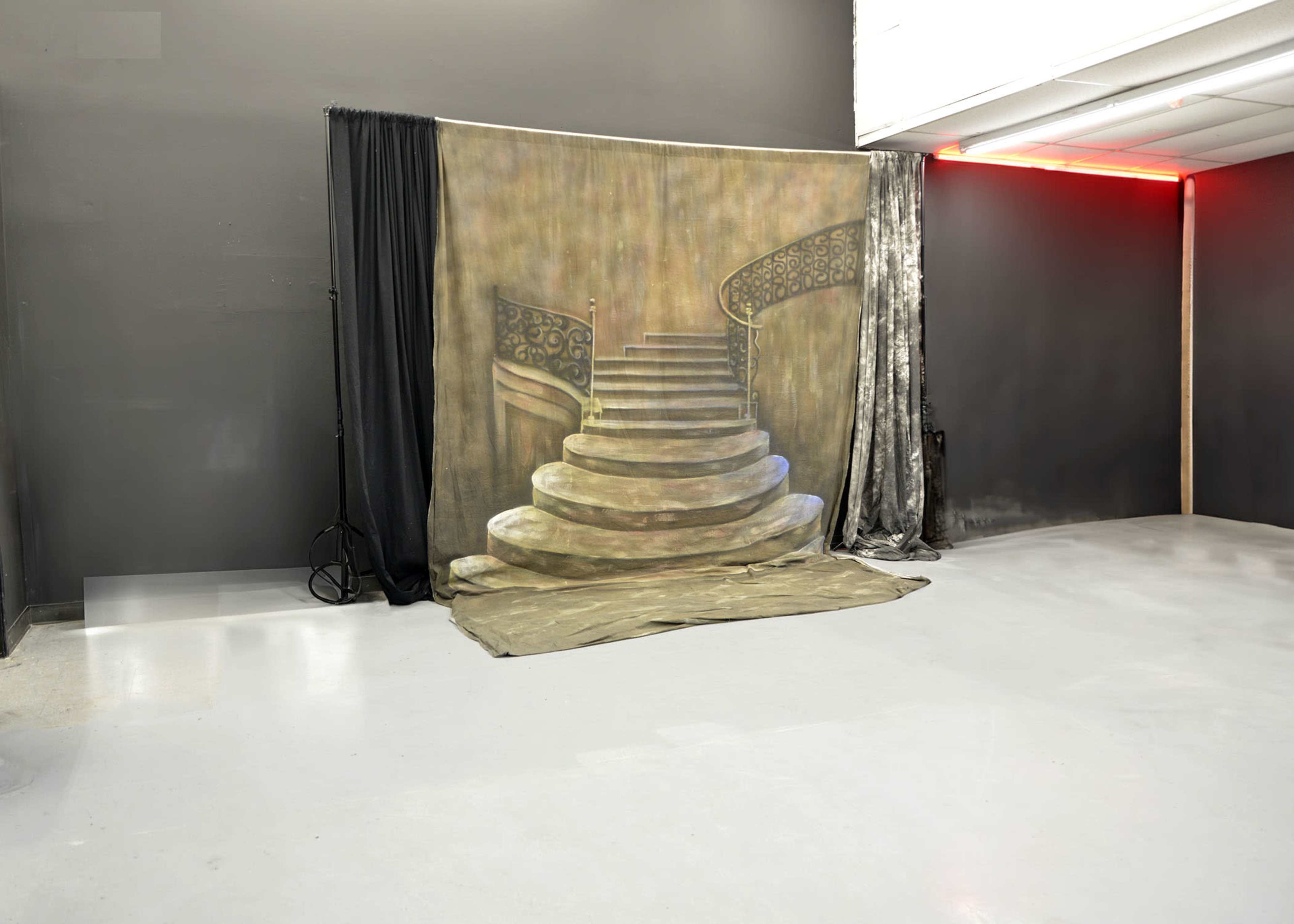 A studio room with a backdrop of a painted spiral staircase.
