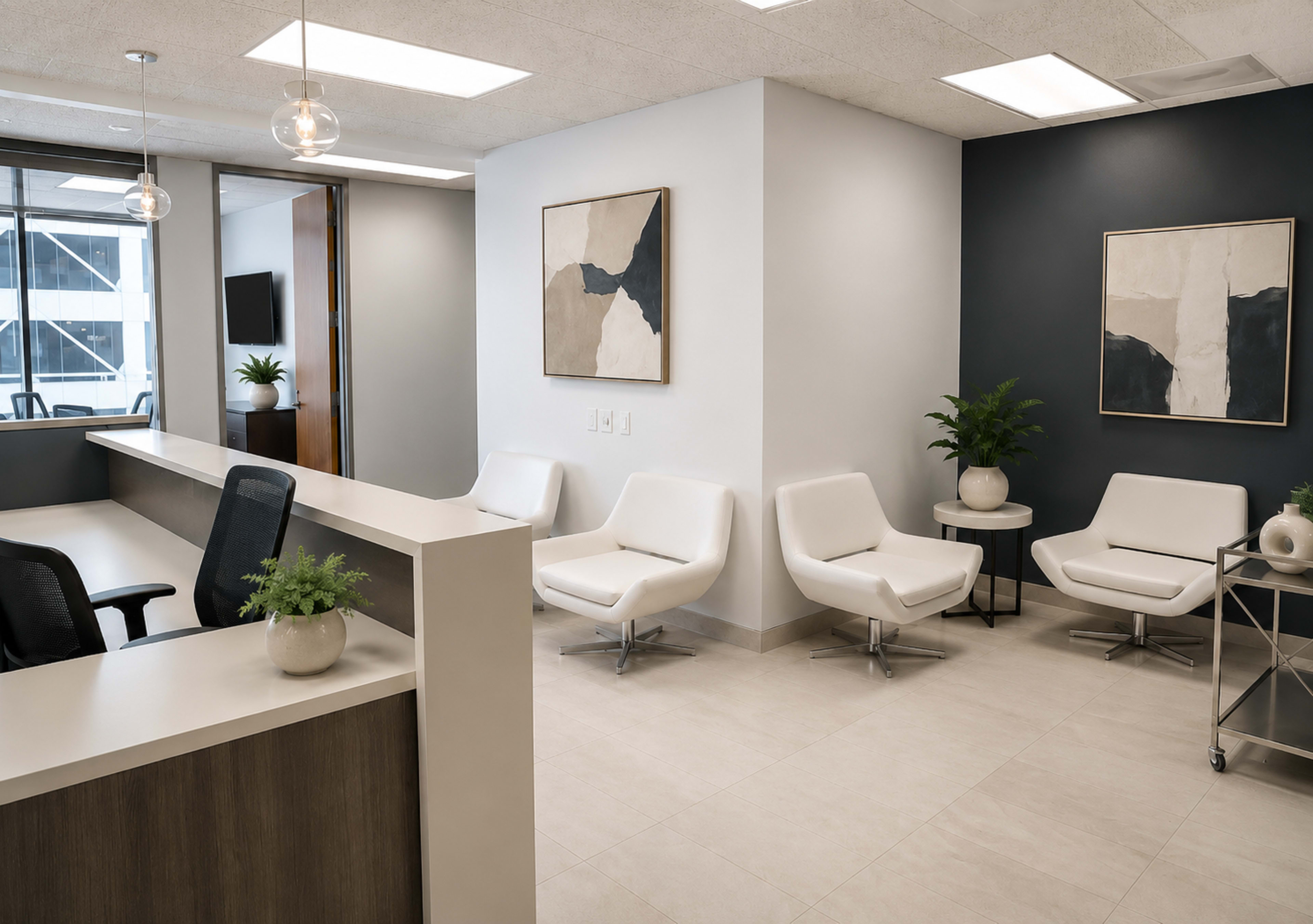 The image shows a modern reception area with a front desk and several minimalist white chairs arranged around a small cart, complemented by abstract art on the walls and greenery in the decor.