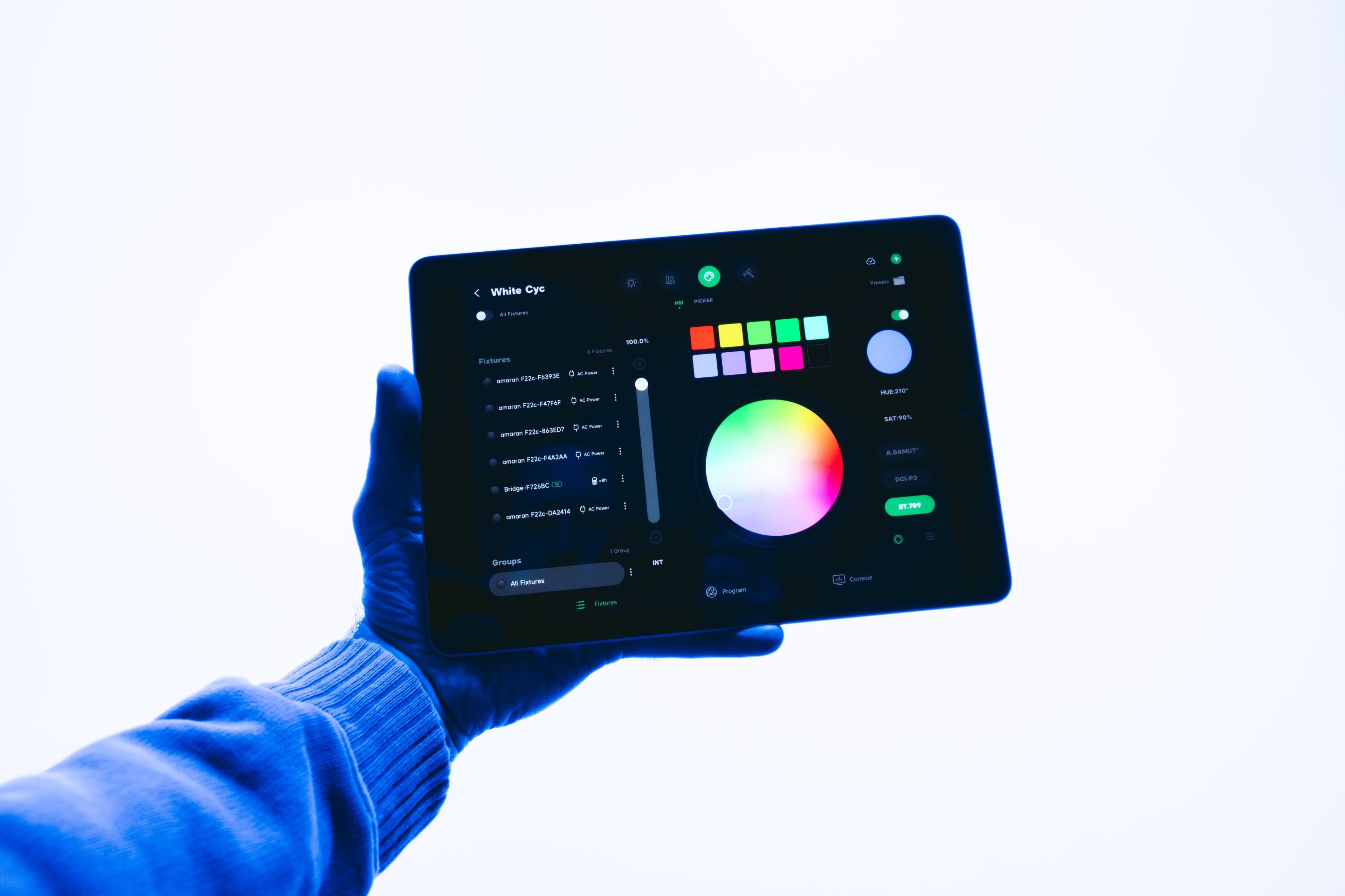 A hand holds a tablet displaying a color selection interface with various color options and sliders.