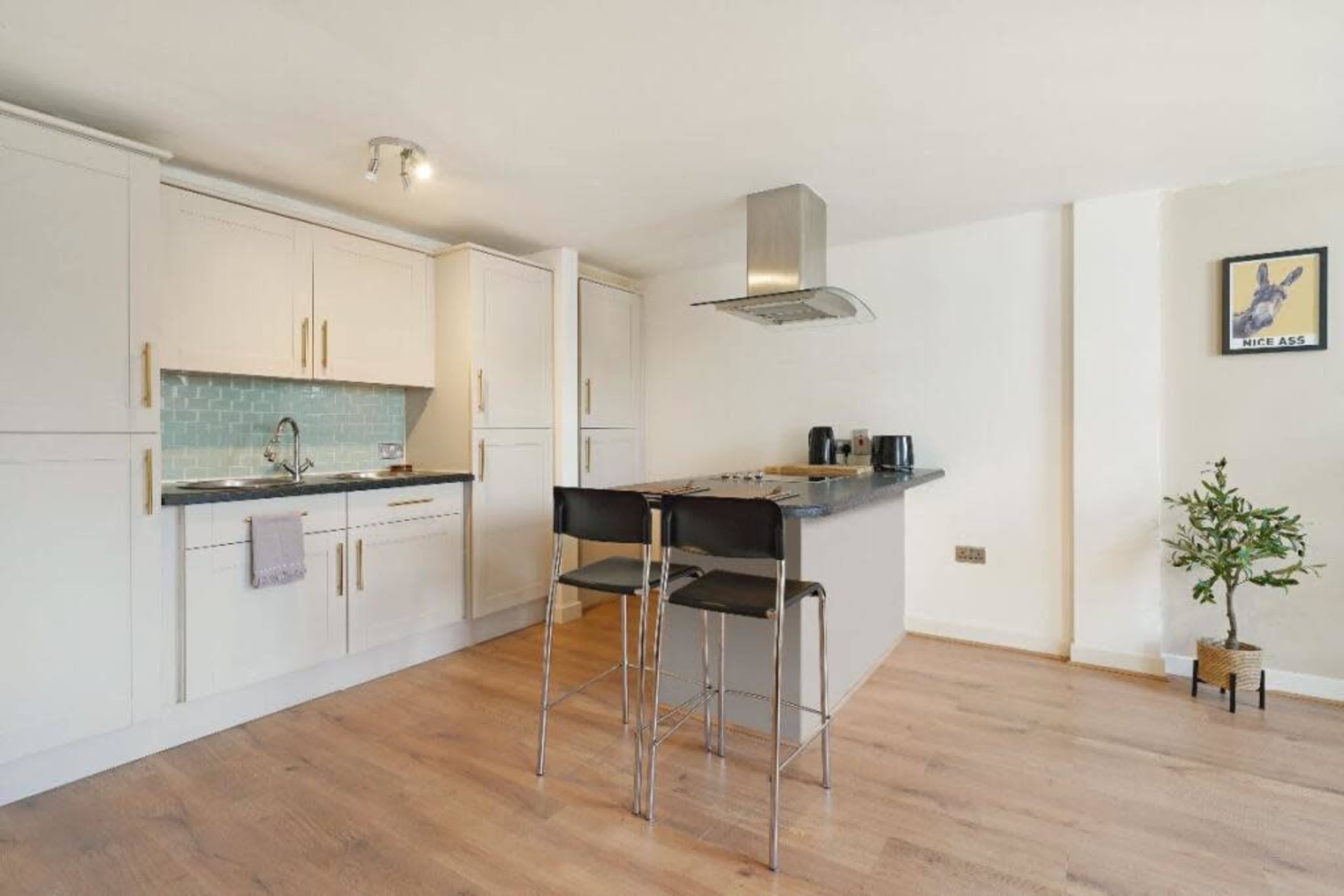 A modern kitchen features white cabinets, a gray countertop, and two stools at a central island.