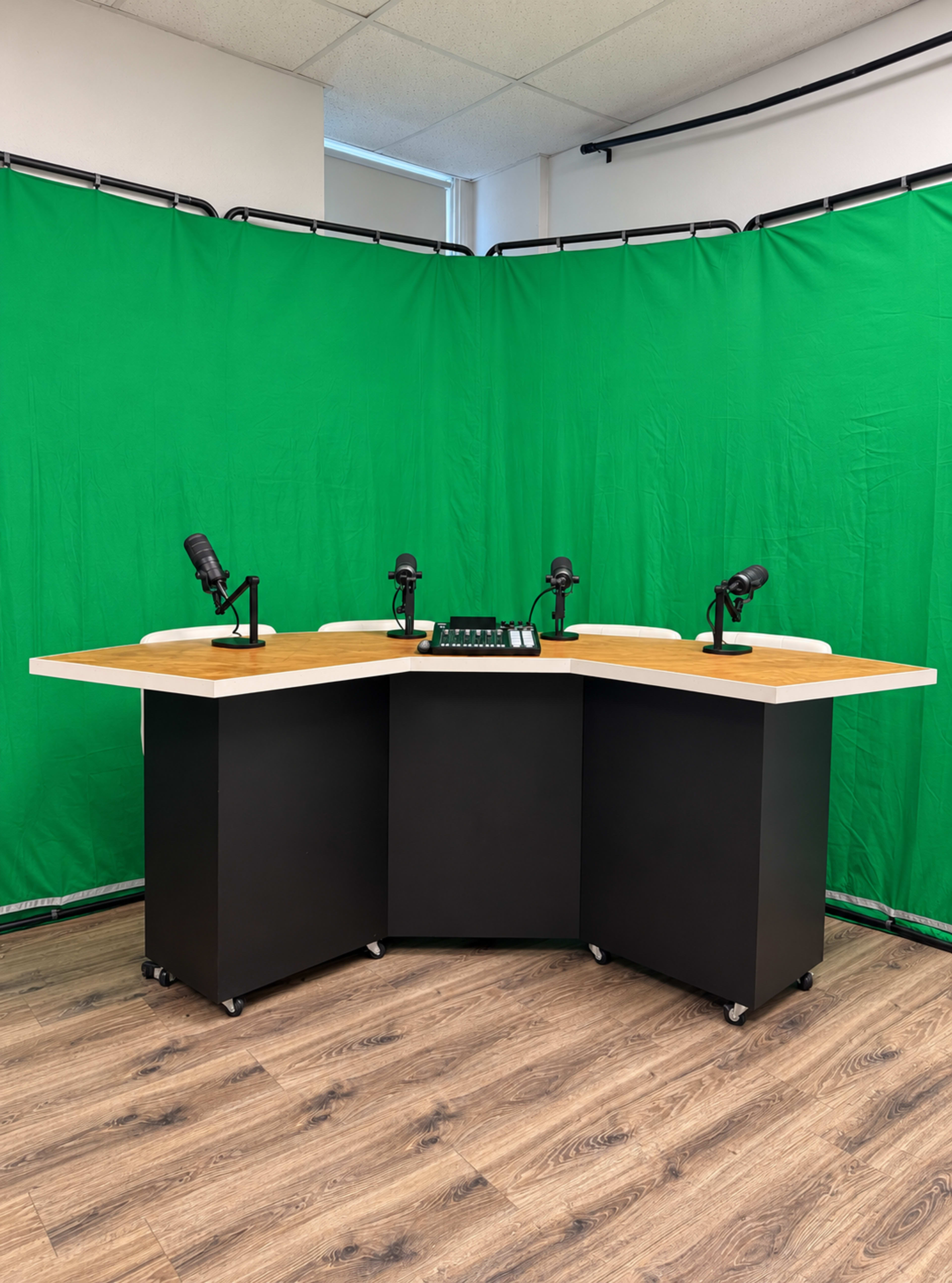 The image shows a podcasting studio setup with a hexagonal table, four microphones, and a green backdrop.