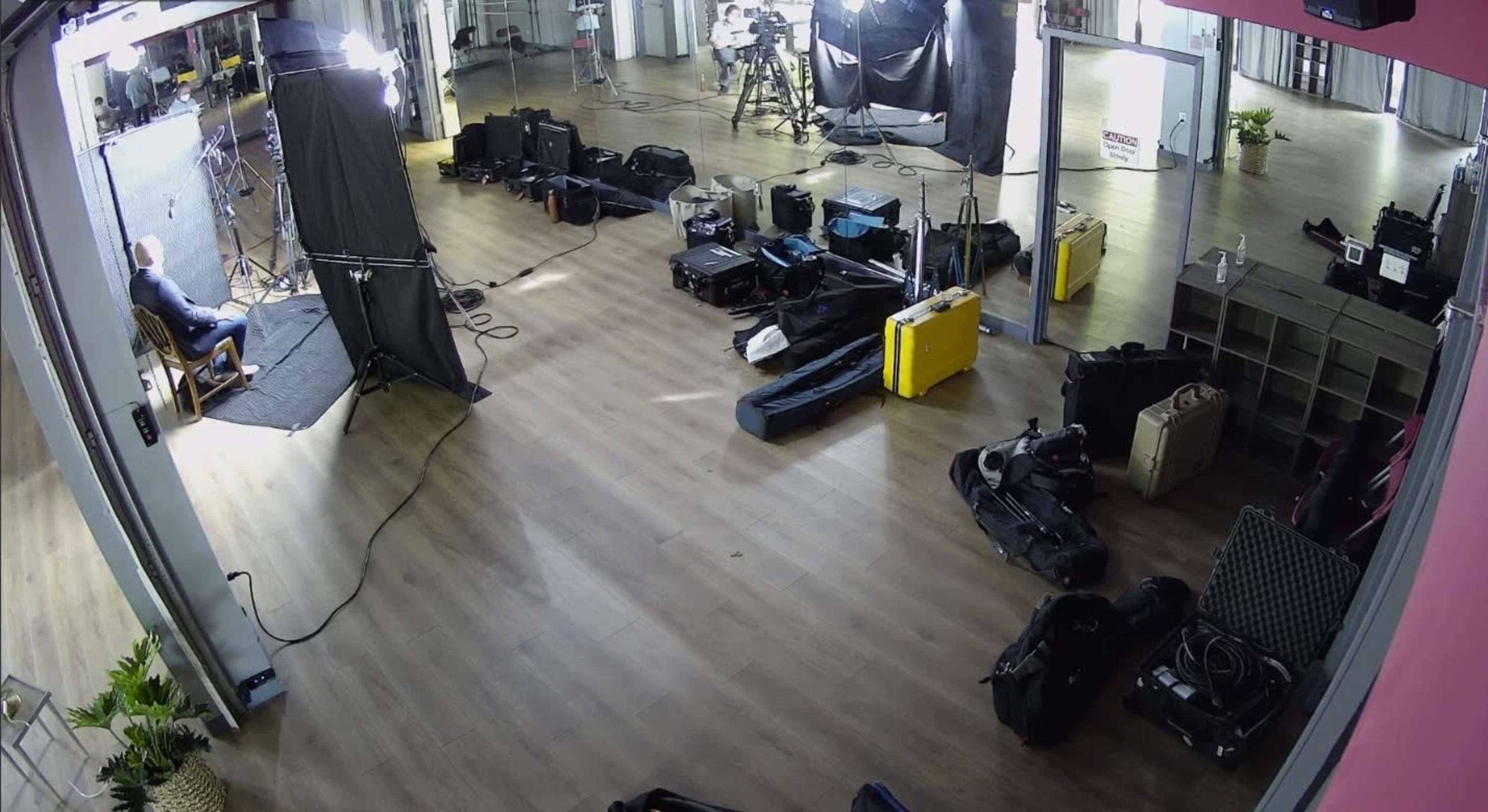 A partially set-up film studio with various equipment cases and lighting positioned around a filming area.