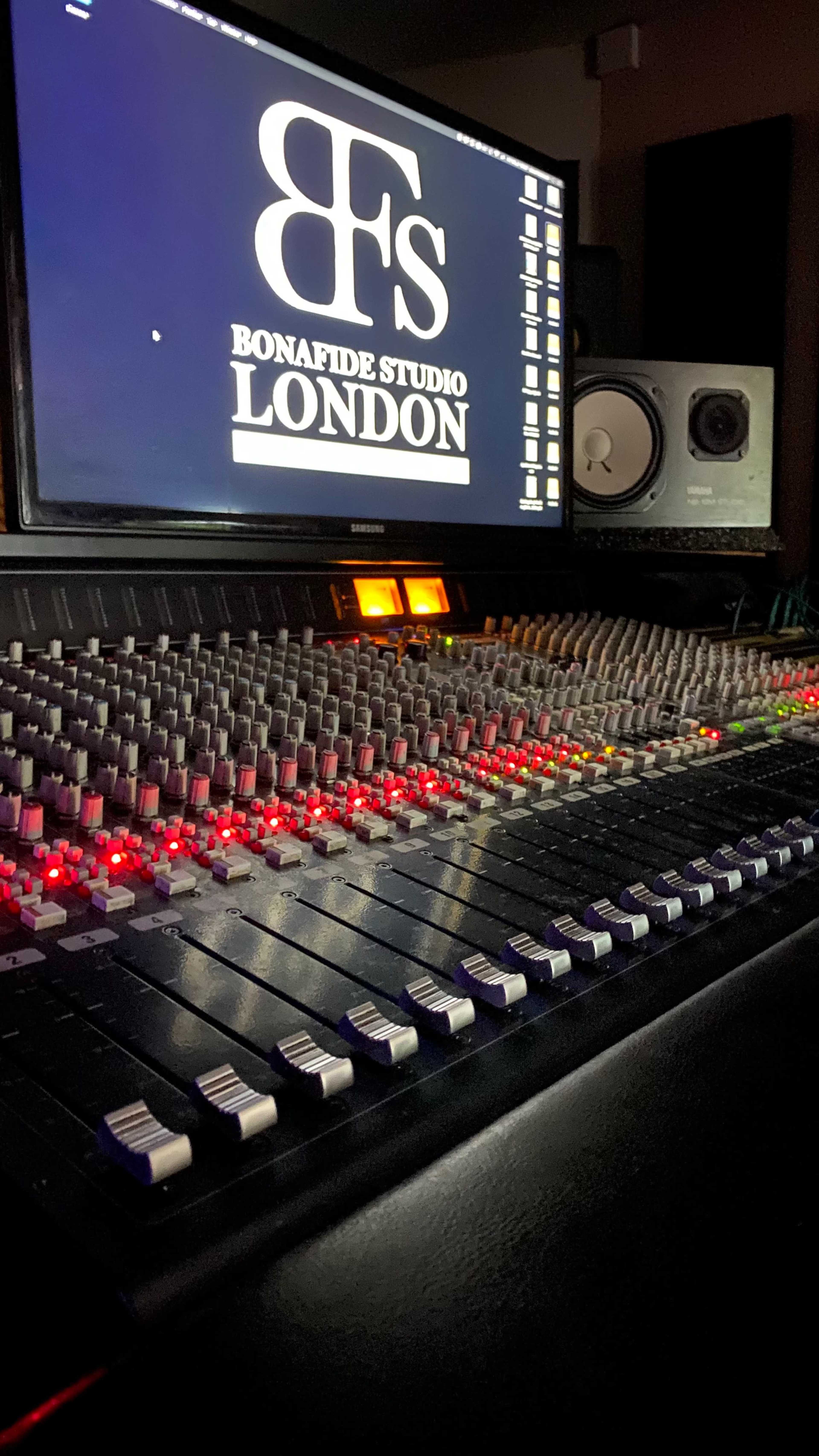 A close-up of a digital audio mixing console in a recording studio, with a computer monitor displaying the logo "Bonafide Studio London" in the background.