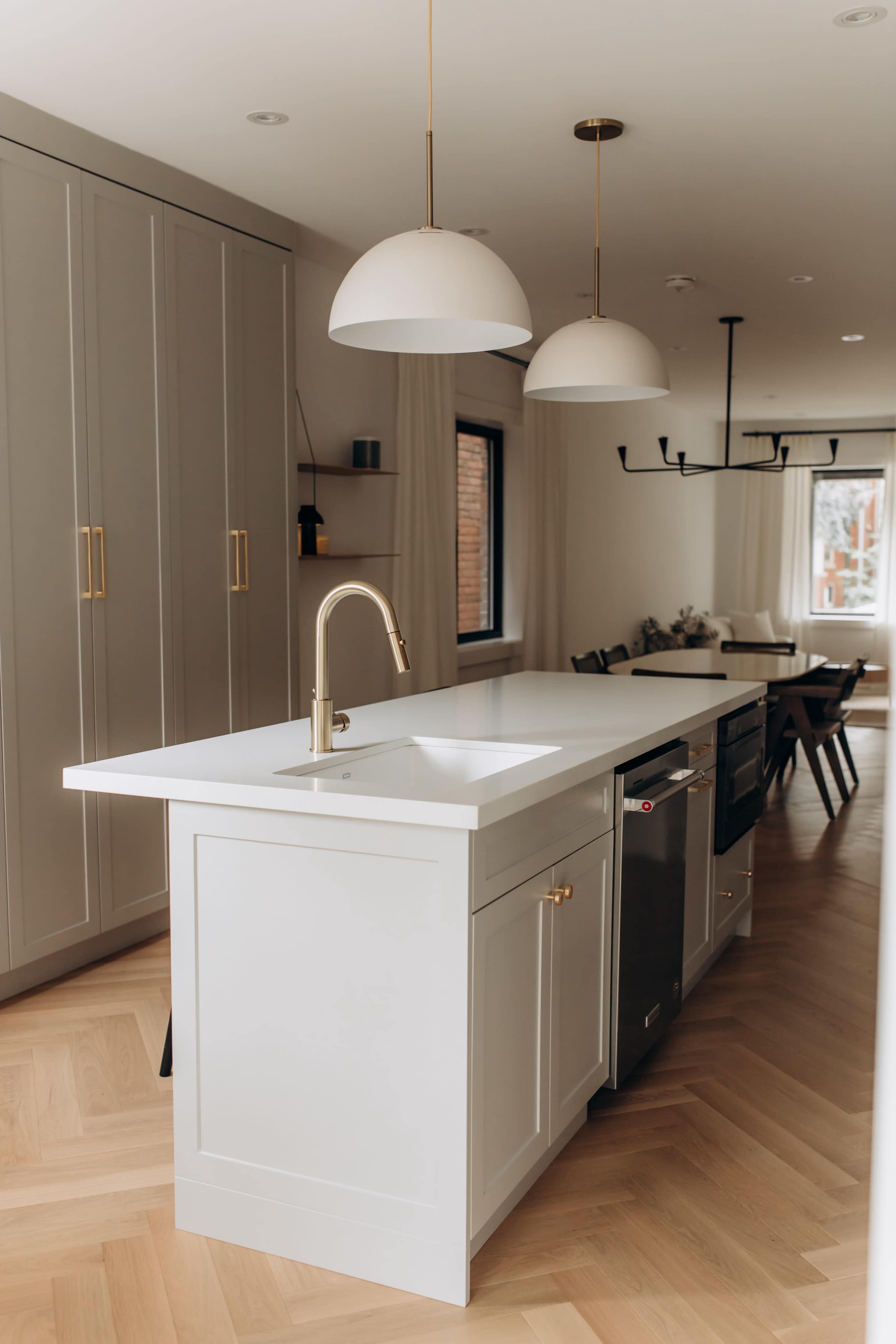 A modern kitchen with a white island, stainless steel appliances, and two pendant lights hanging above.