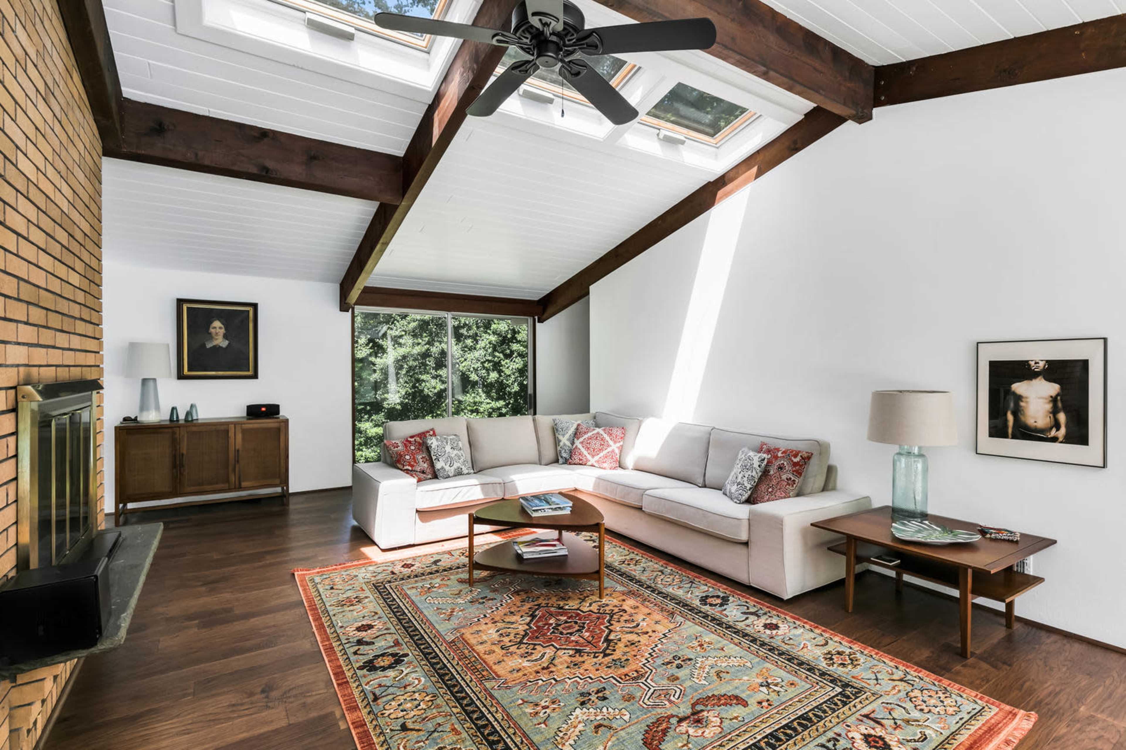 A modern living room with a sectional sofa, a coffee table, and large windows that let in natural light.