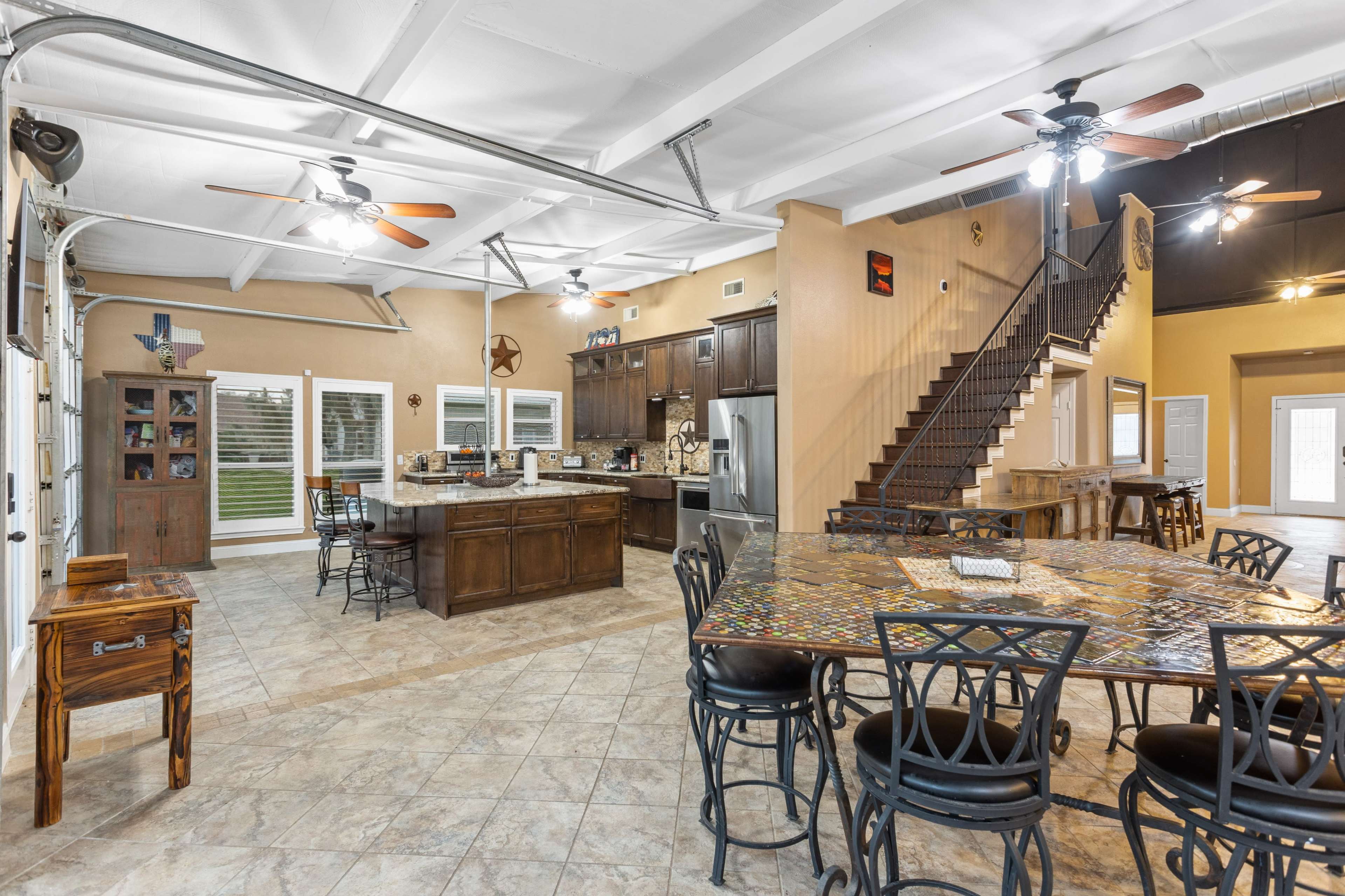 A spacious, open-concept kitchen and dining area with a large table, modern appliances, and a staircase leading to an upper level.