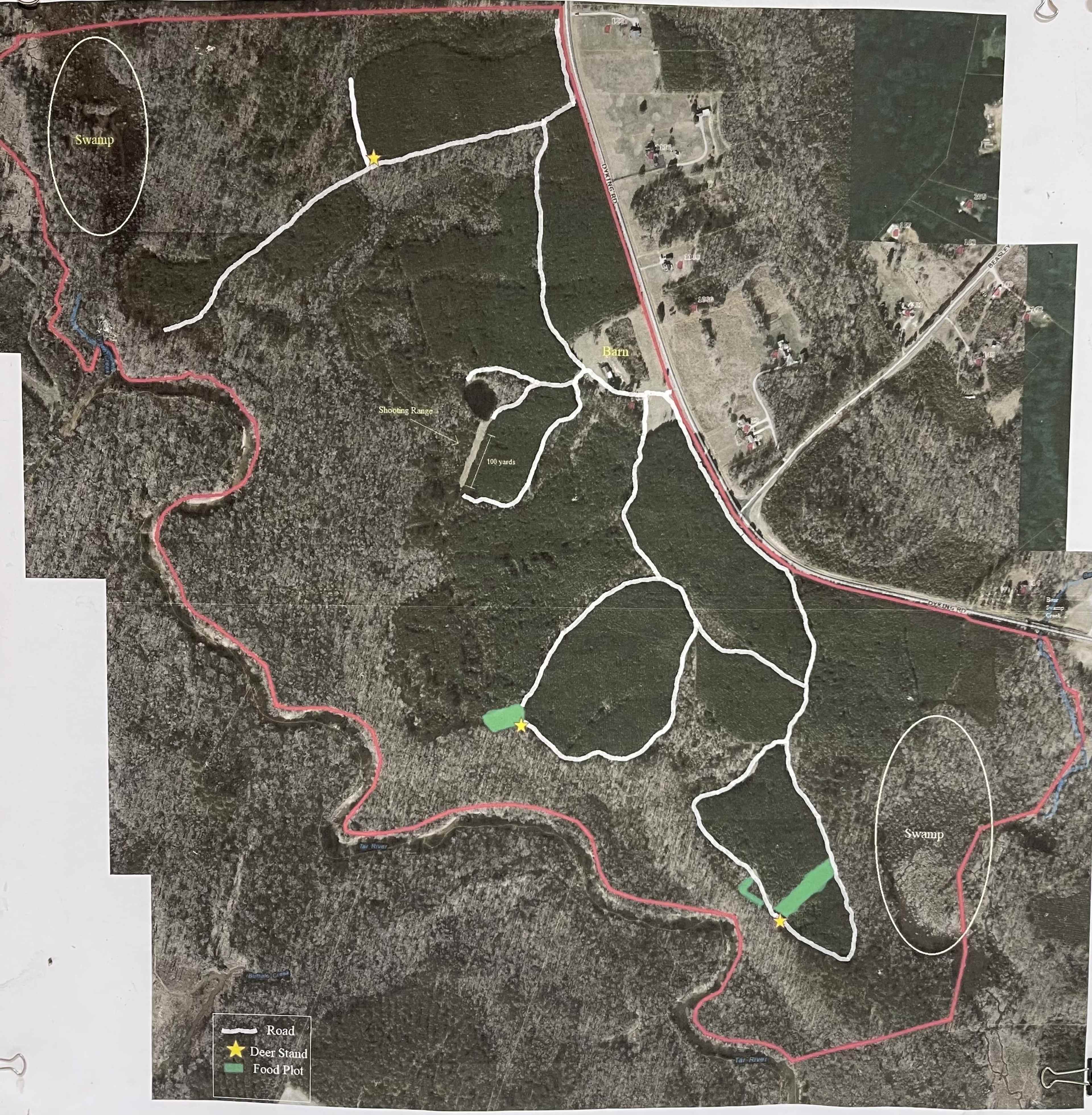 The image displays a map of a wooded area with marked trails, roads, and points of interest outlined in white and green.