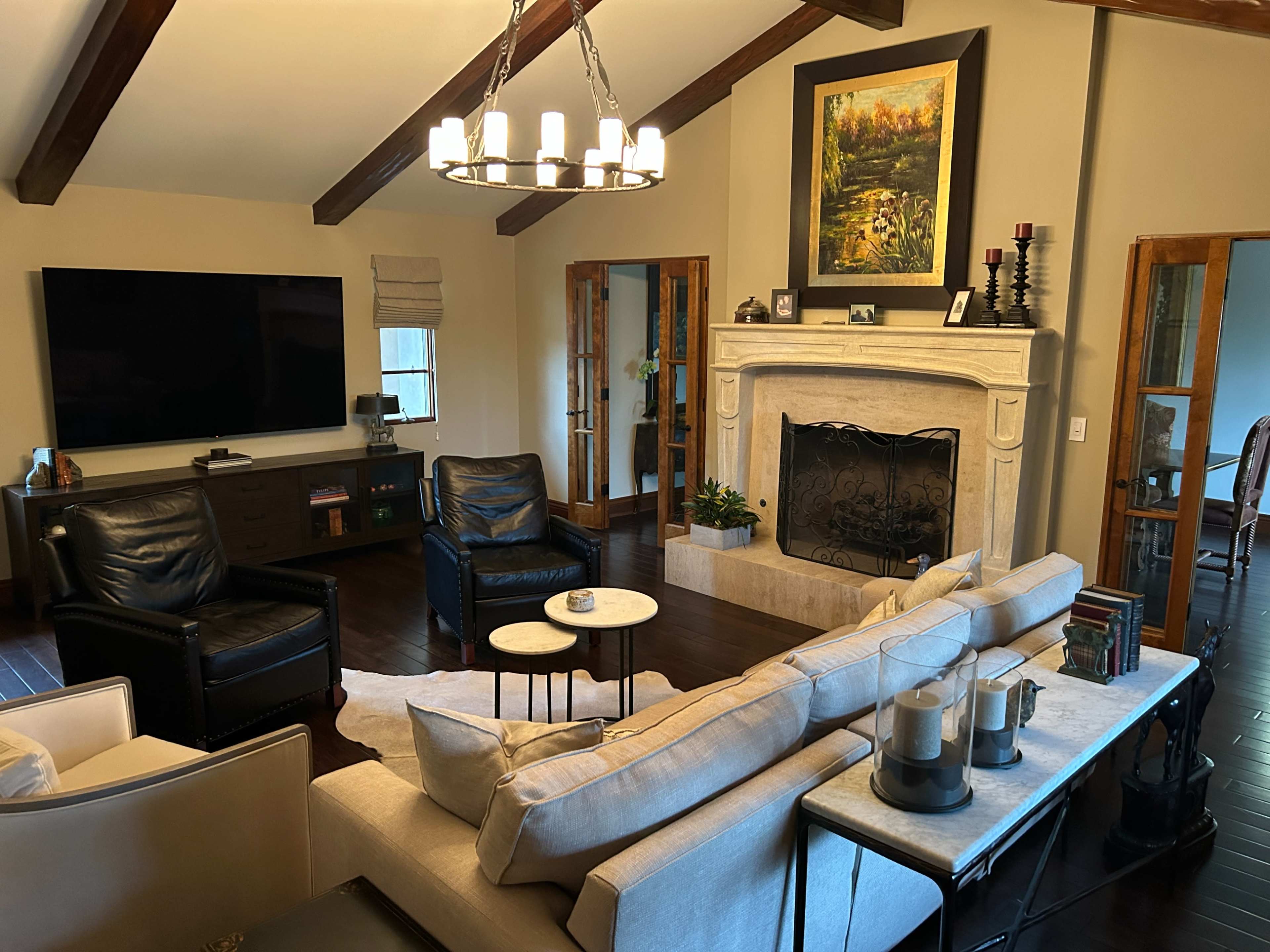 The living room features a large sectional sofa, two armchairs, a coffee table, and a fireplace with a decorative mantle, all set against a backdrop of vaulted ceilings and a large wall-mounted television.