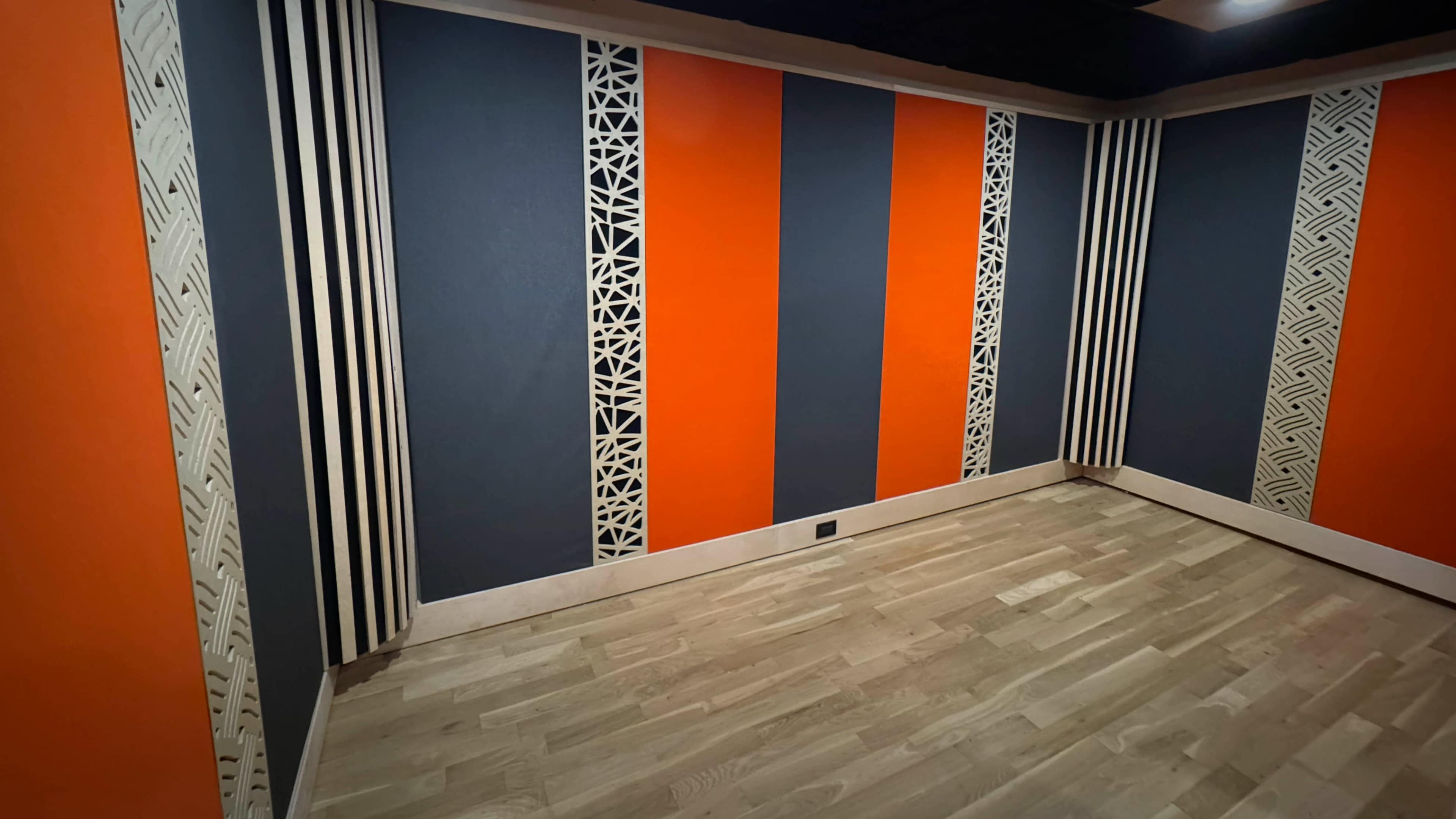 The image shows a corner of a room with a hardwood floor and walls painted in alternating orange and dark blue sections, featuring decorative elements along the edges.