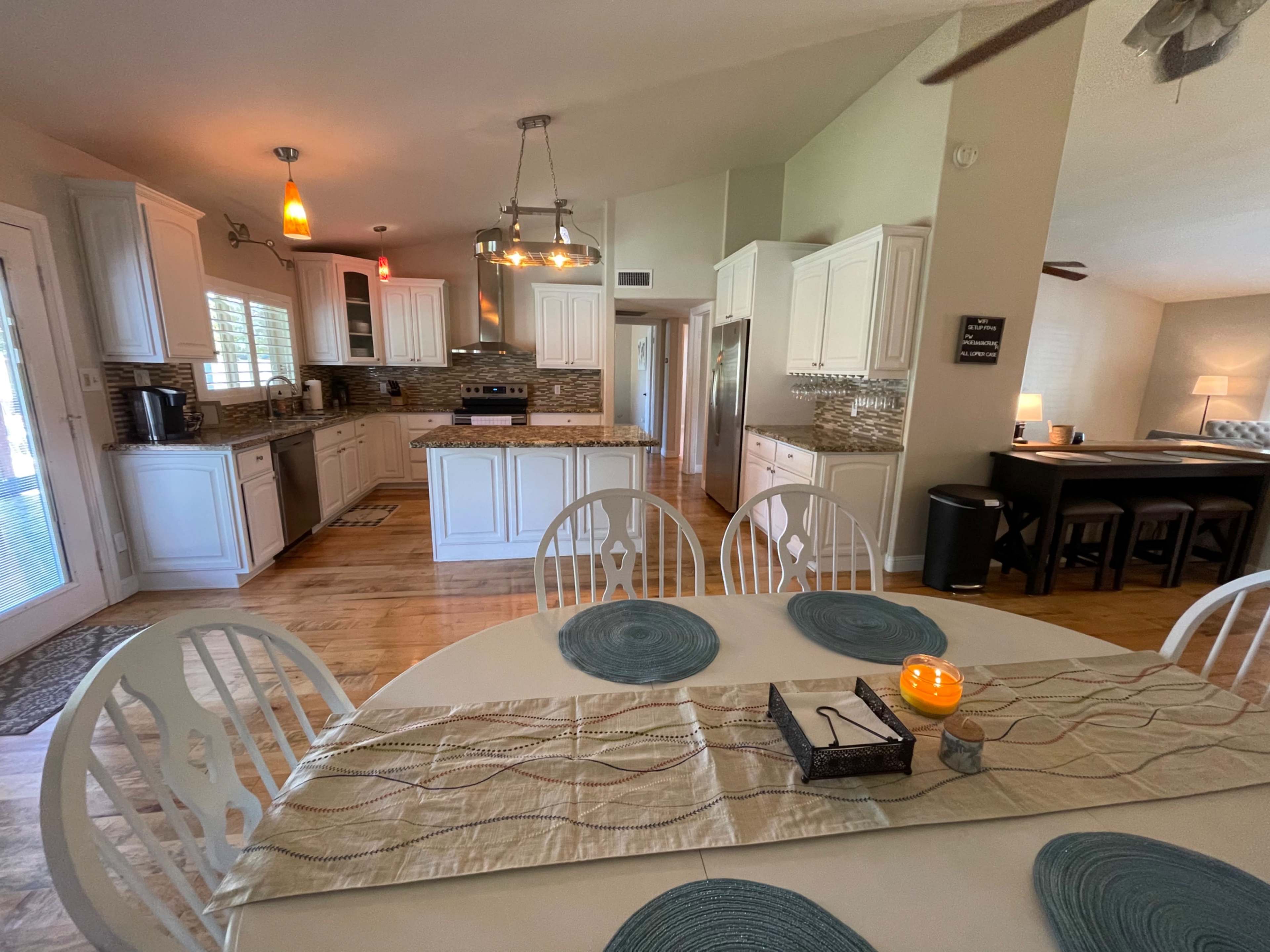 A bright kitchen and dining area featuring white cabinets, a circular dining table set with placemats, and modern appliances.