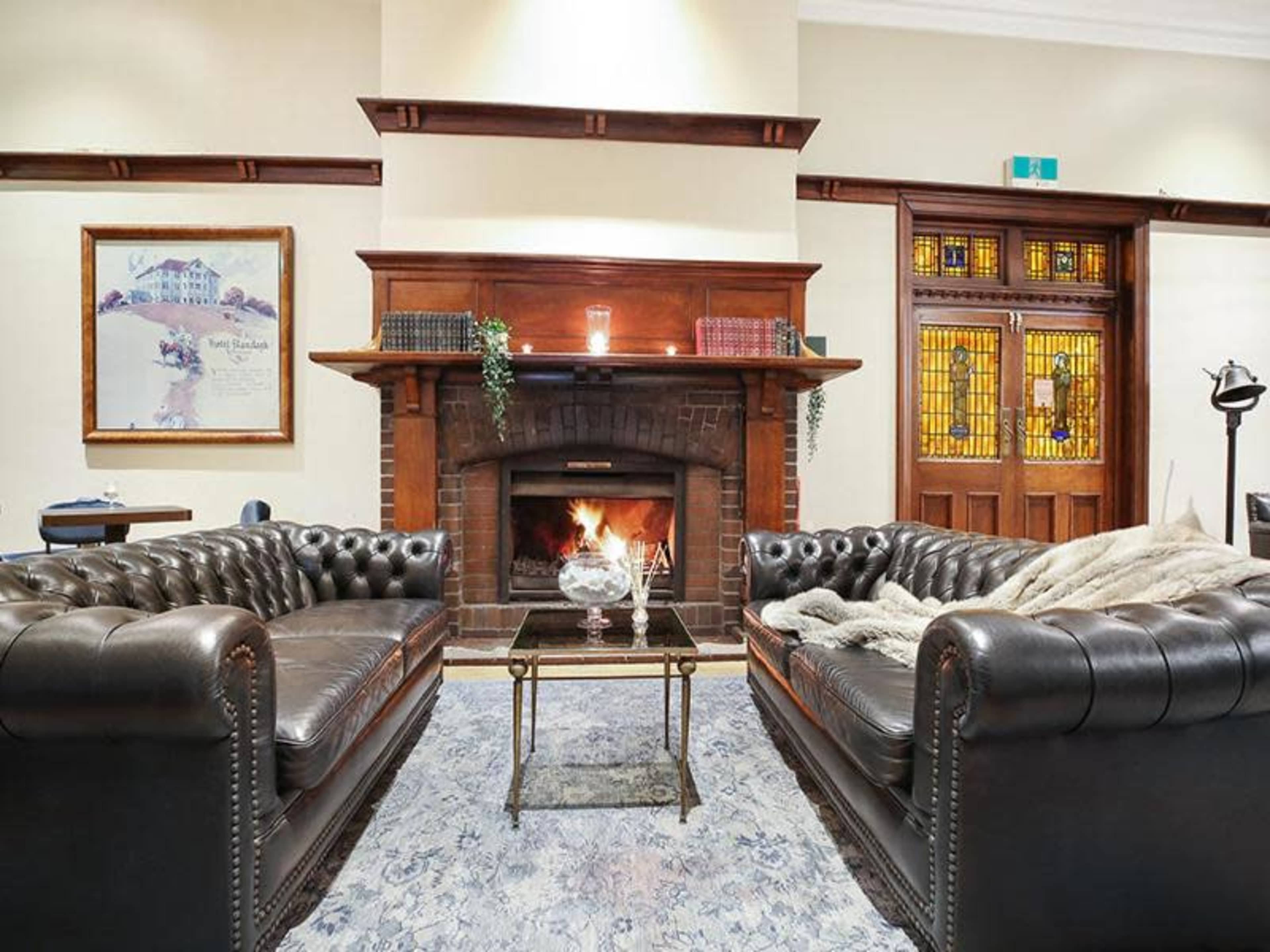 A cozy living room features two leather couches facing a glass coffee table, with a fireplace adorned in the background.