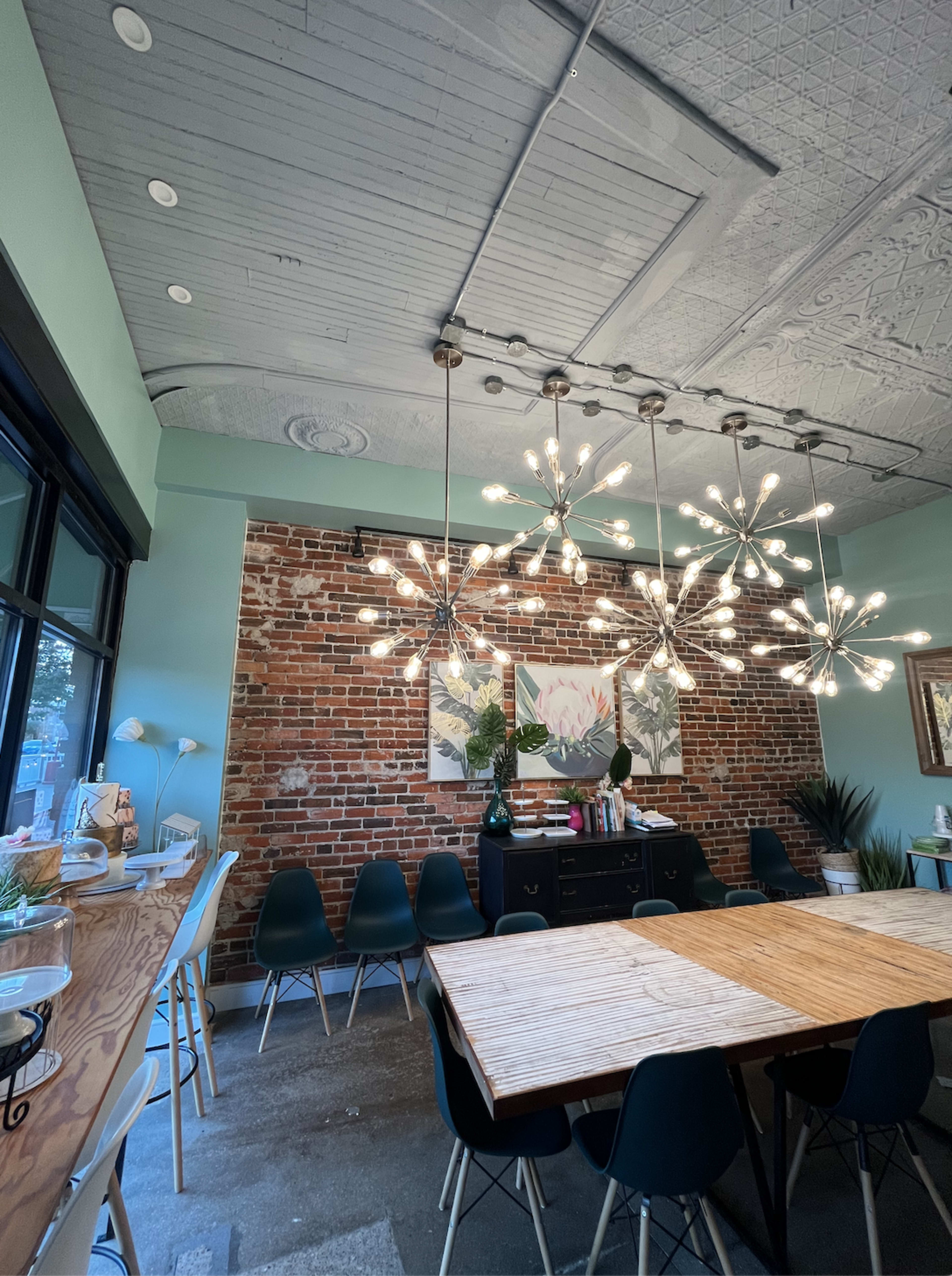 A modern room with exposed brick walls, a large wooden table at the center, and striking pendant lights hanging from the ceiling.