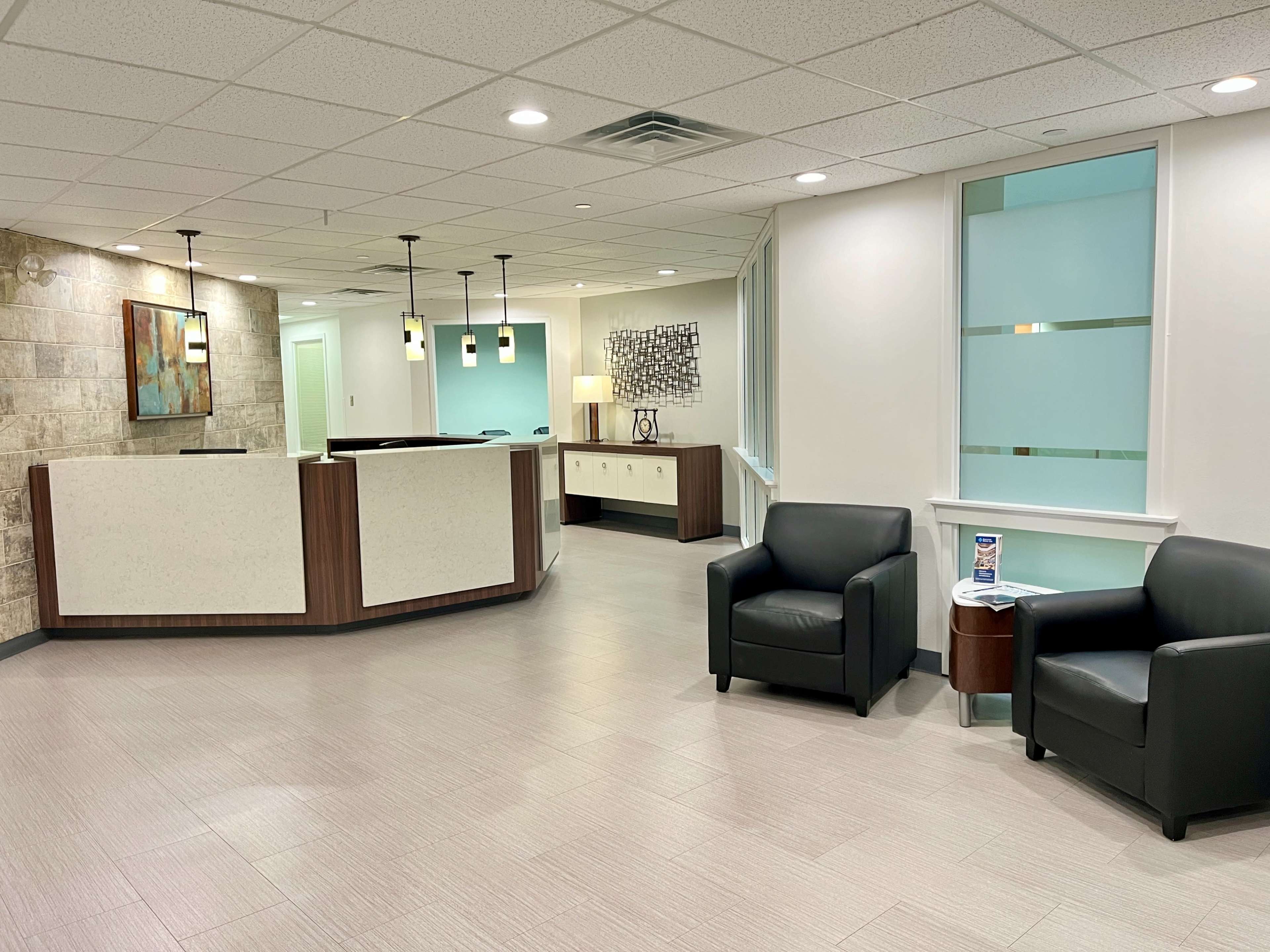 The image shows a modern reception area with a front desk, seating, and light-colored walls.