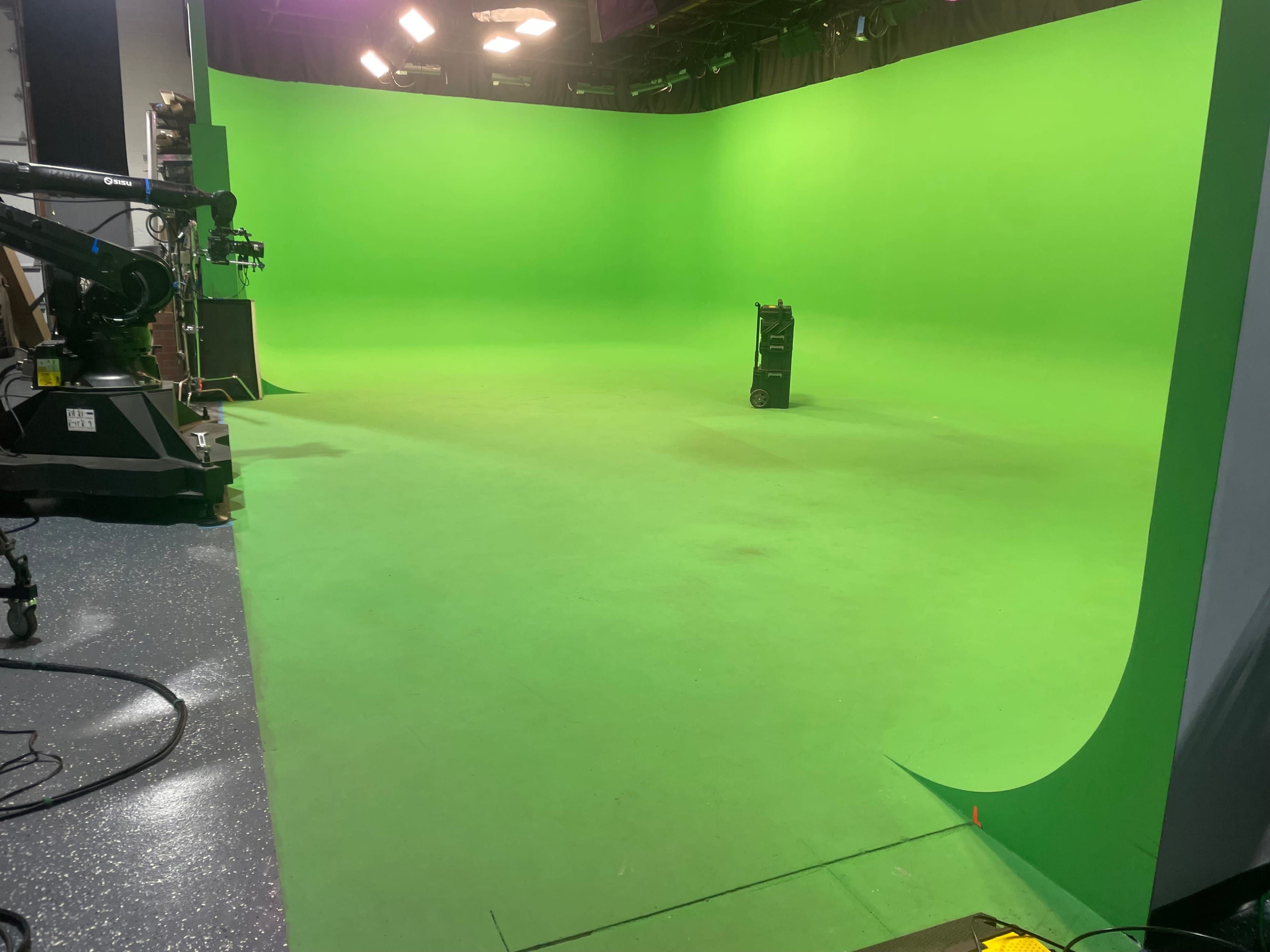 The image shows an empty green screen studio with a single cart positioned in the center.