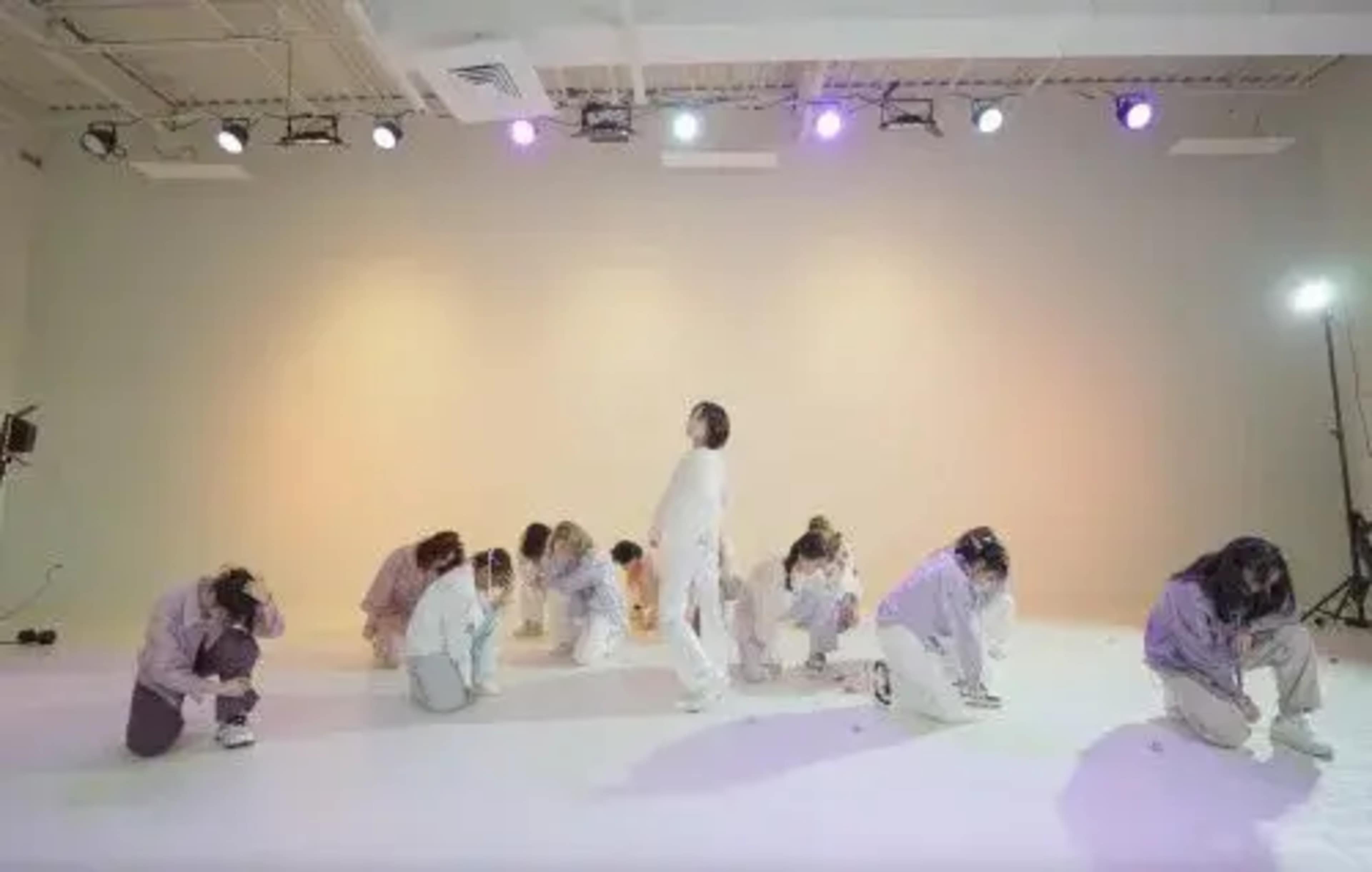 A group of dancers in matching outfits performs a choreographed routine on a stage illuminated by colorful lights.