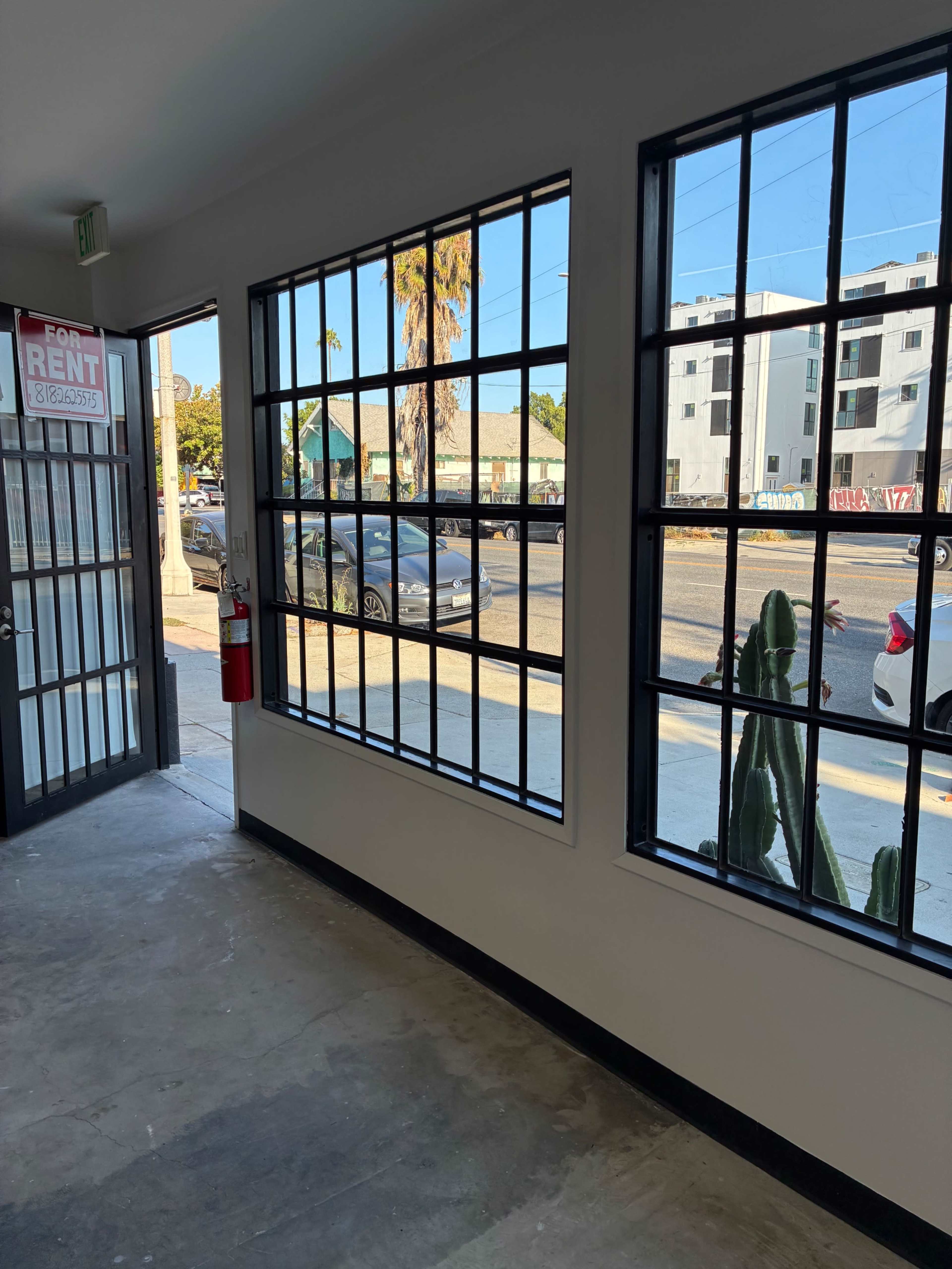 Empty modern storefront commercial space with concrete floors, large custom steel windows and oversized door. Image in South Los Angeles, Los Angeles, CA