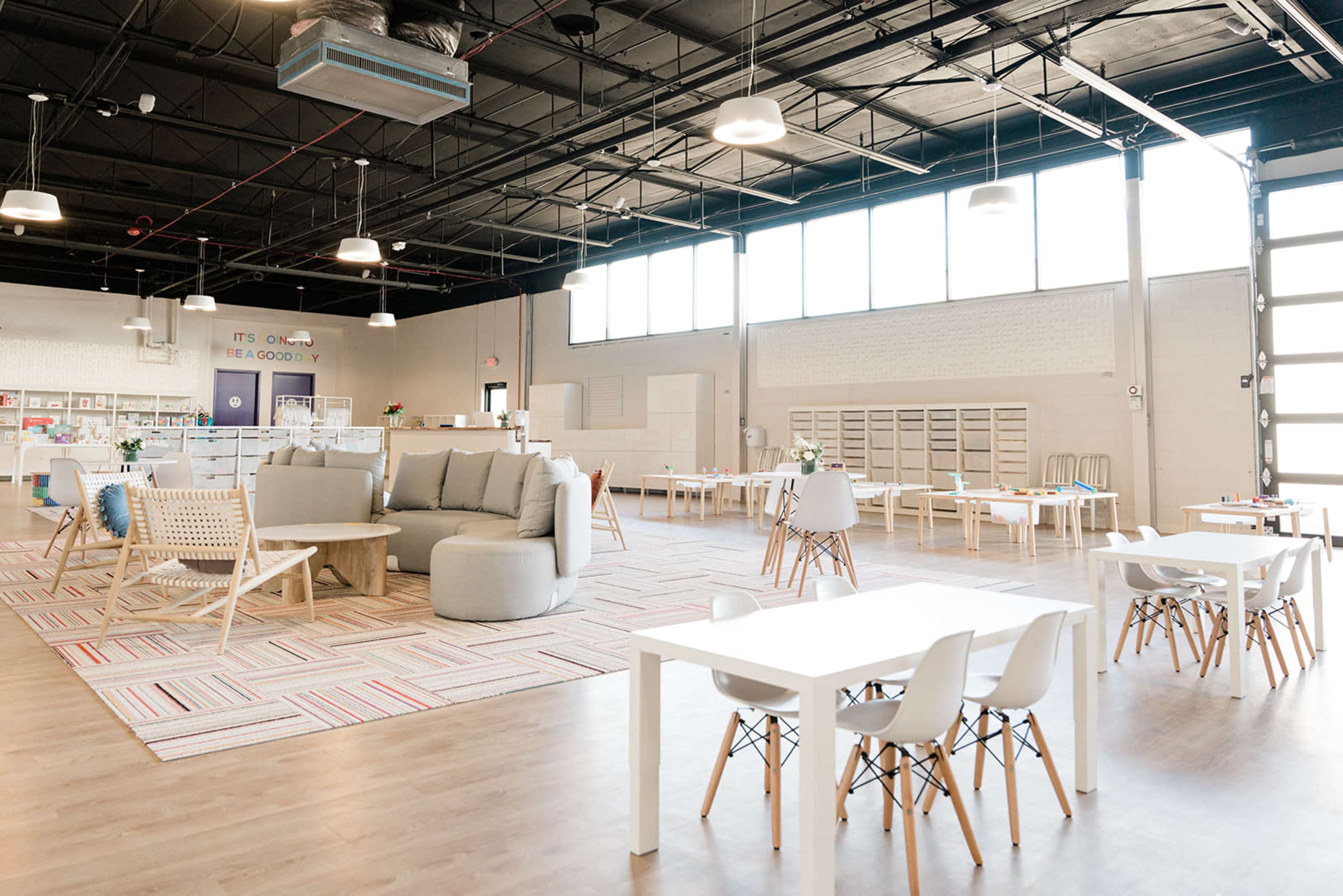A spacious, well-lit interior of a modern workspace with various seating arrangements and tables.