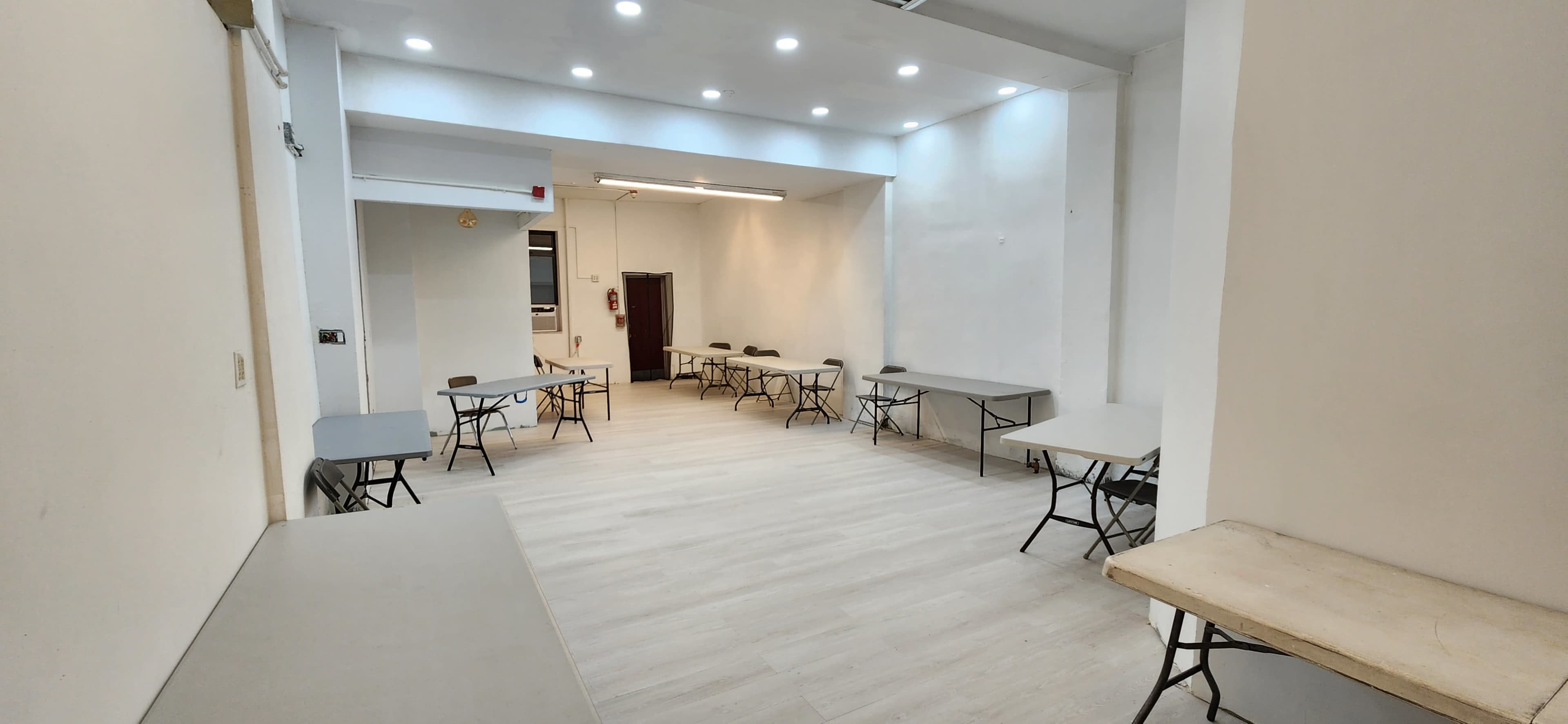 A spacious, well-lit room with several folding tables arranged in a neat layout.
