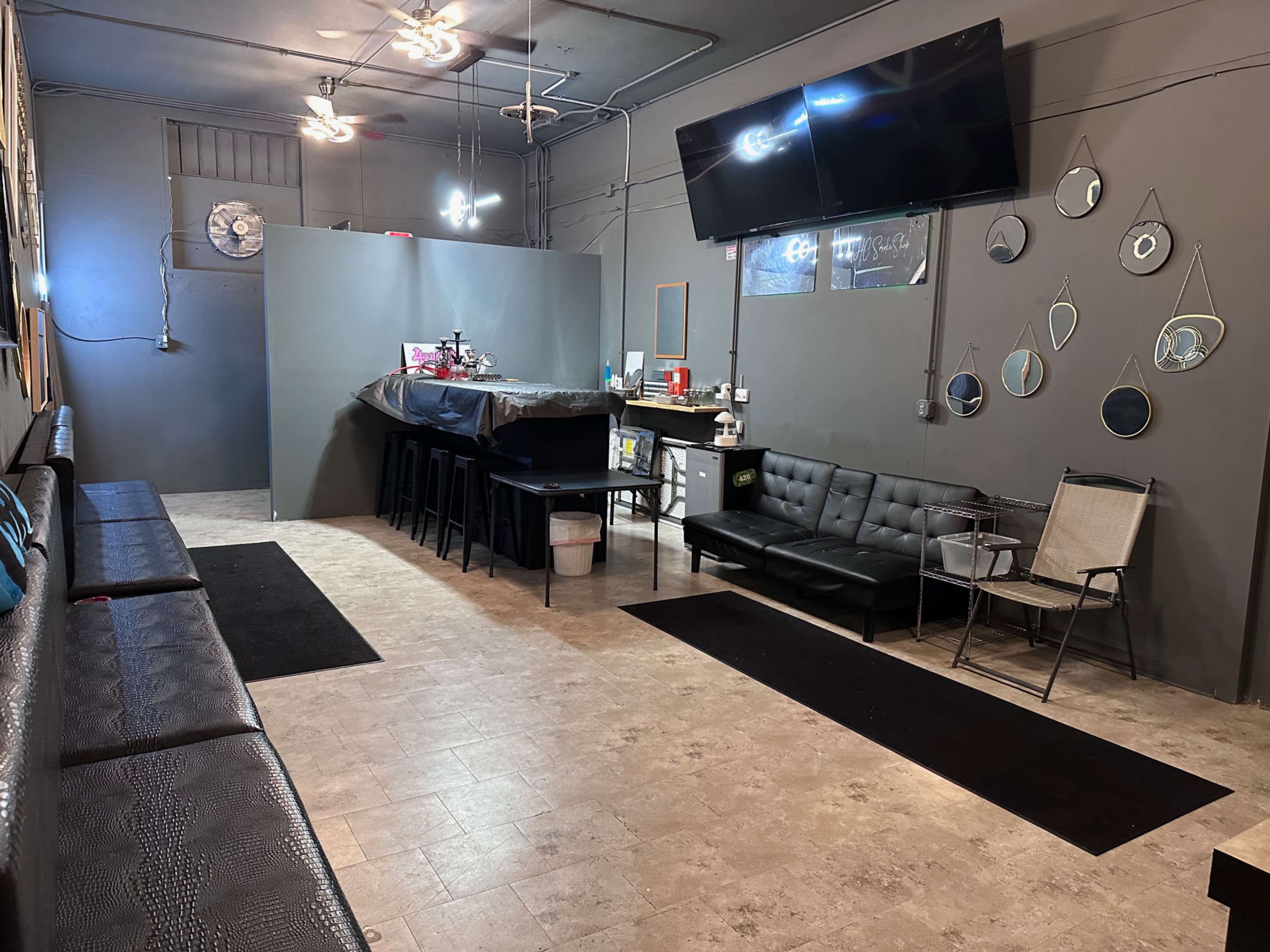 The image shows a waiting area with sleek benches along the walls, a bar-like counter in the back, and several mirrors on one wall.