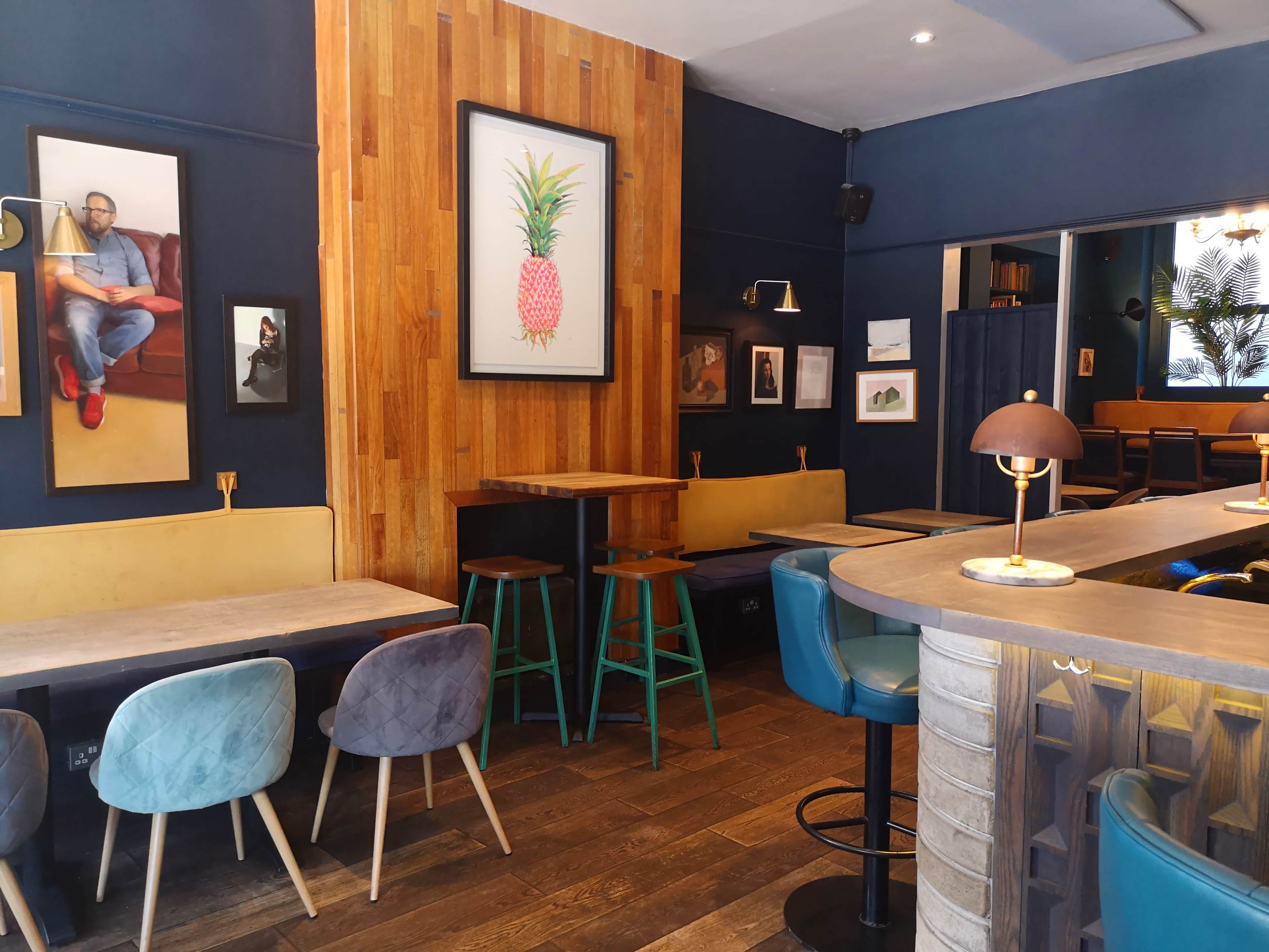 The image shows a cozy café interior with wooden accents, including tables and wall art depicting various subjects.