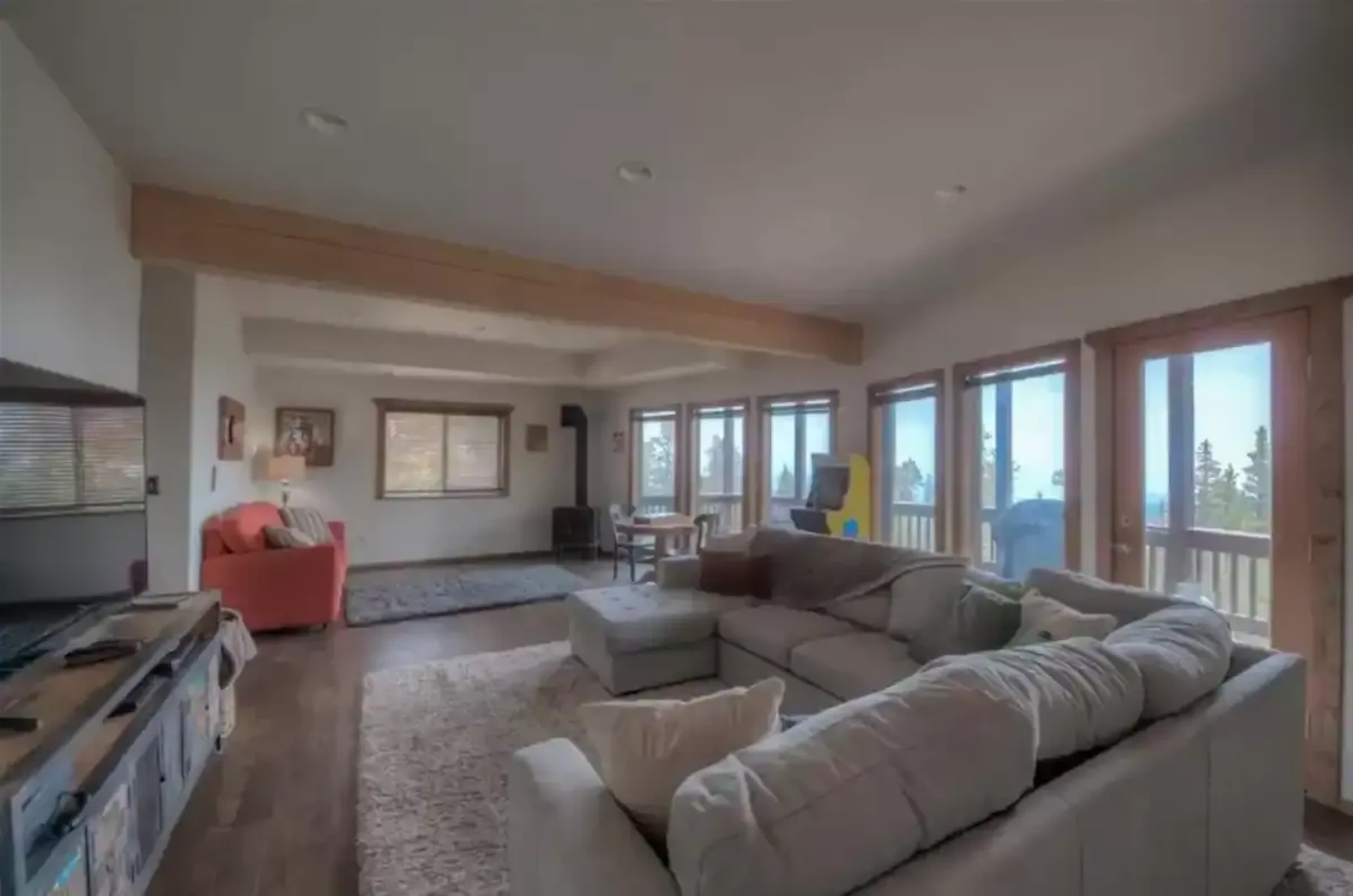 A spacious living room with large windows, a sectional couch, and a dining area.