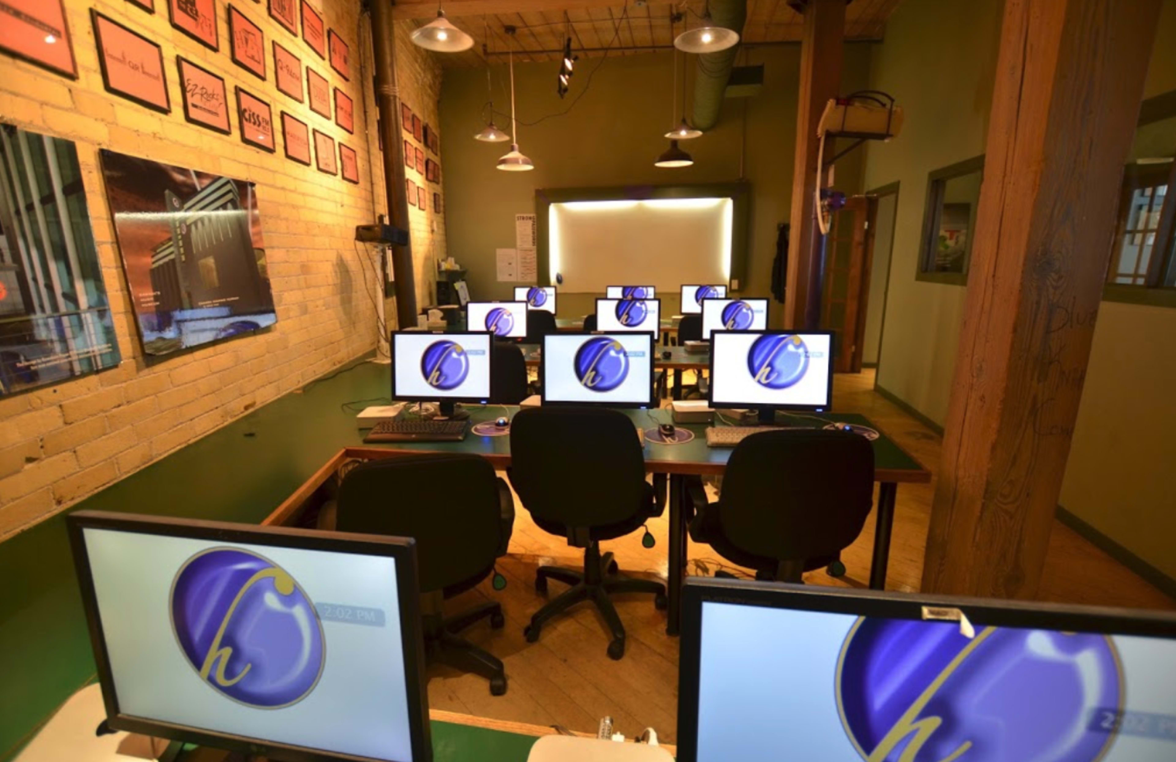 A computer lab with several workstations, each equipped with a monitor displaying a logo.