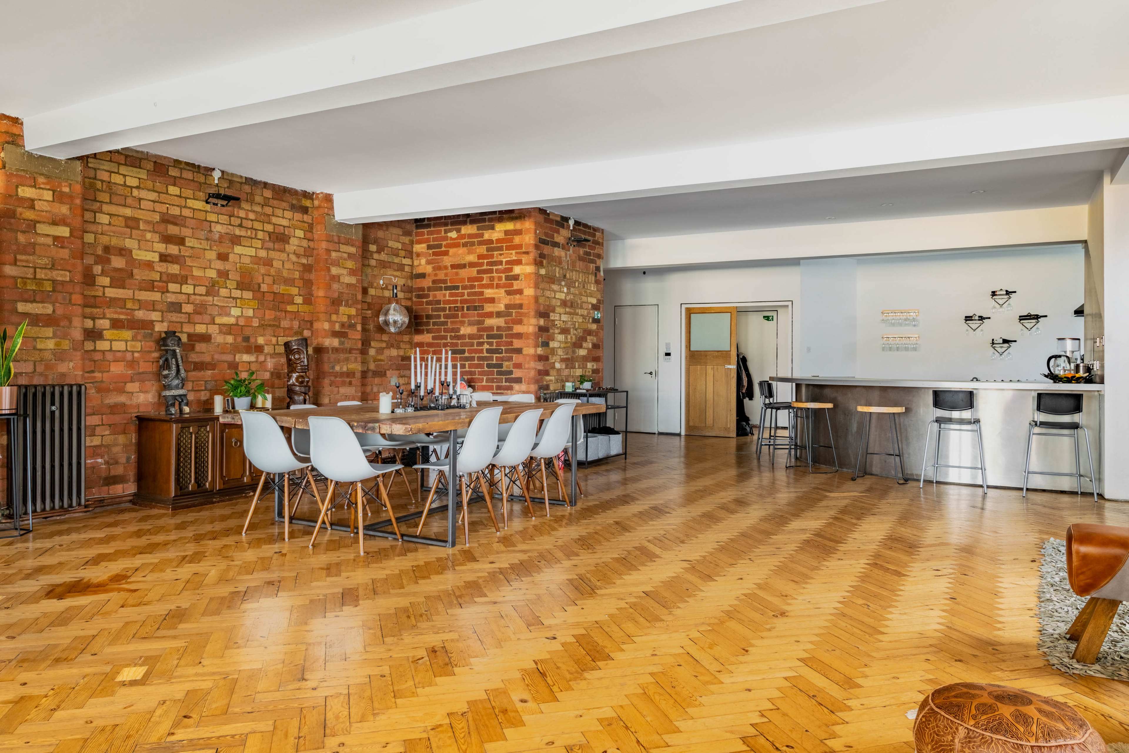 A spacious interior with exposed brick walls, a dining table set for six, and a kitchen area with bar seating.