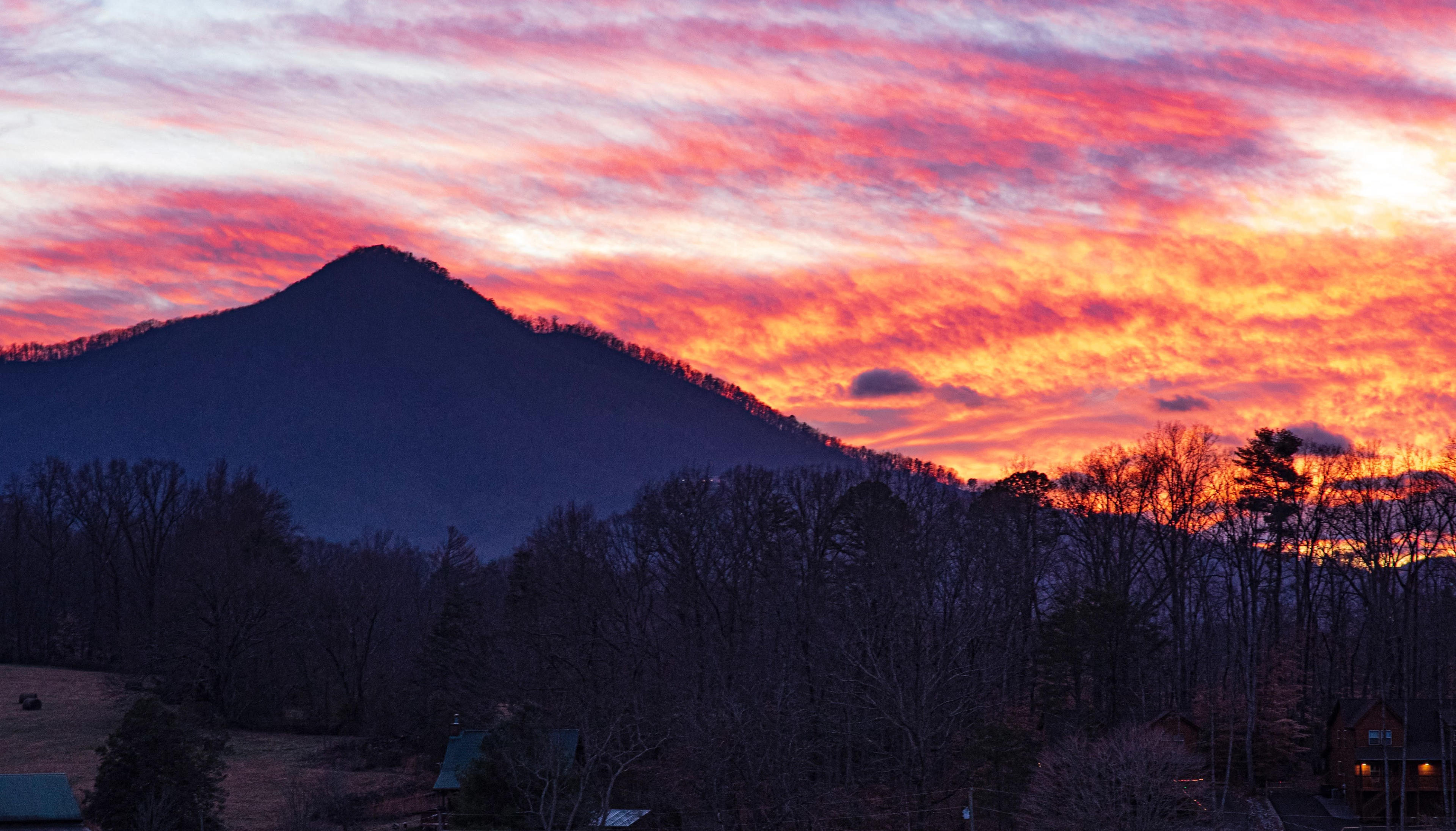 A mountain rises against a vibrant sunset with colorful clouds filling the sky.
