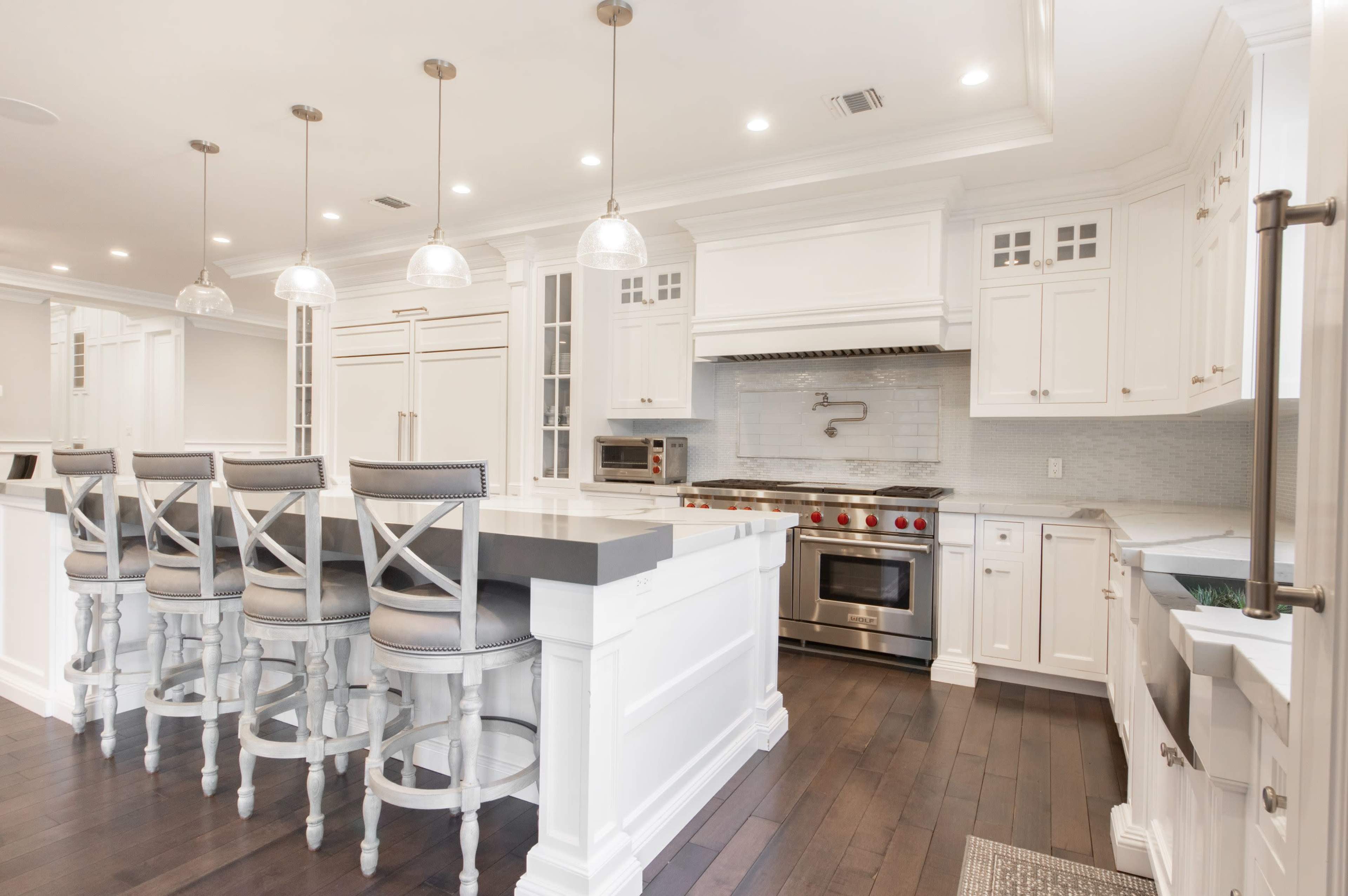 A modern kitchen features white cabinetry, stainless steel appliances, and a large island with bar seating.