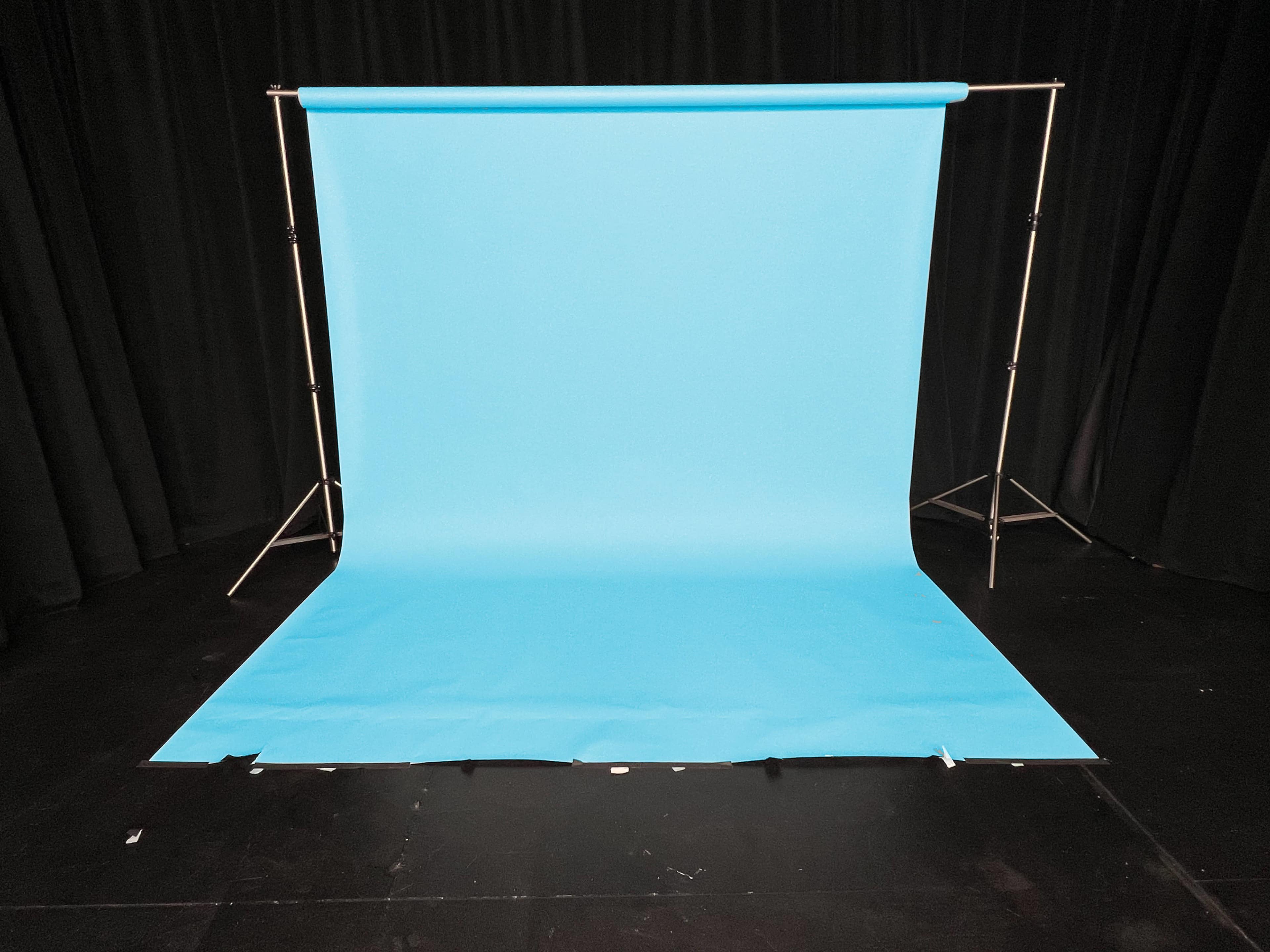 A light blue backdrop is set up on a black stage with a smooth, unwrinkled surface.