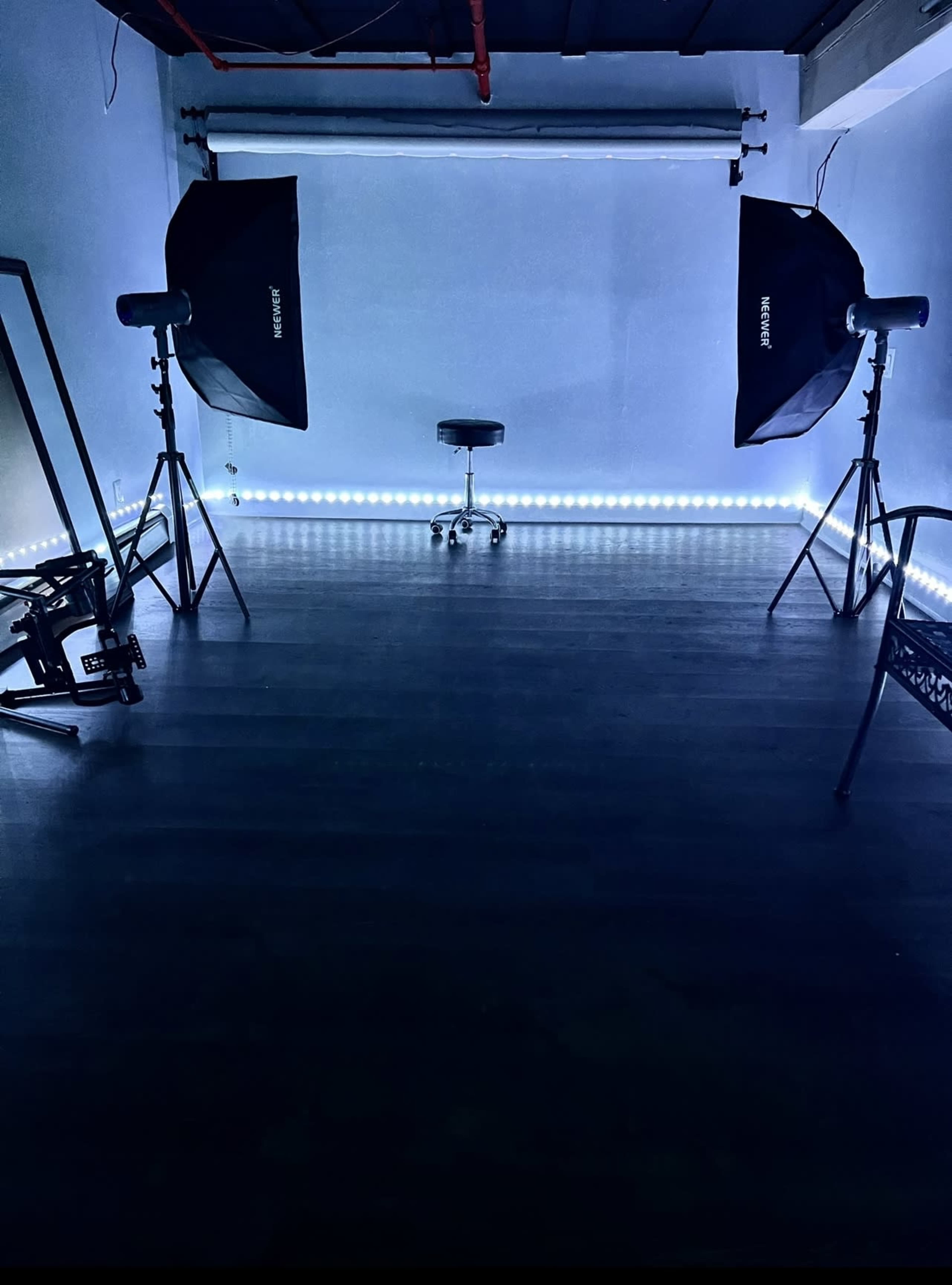 A photography studio with lighting equipment positioned around a central stool on a dark floor.