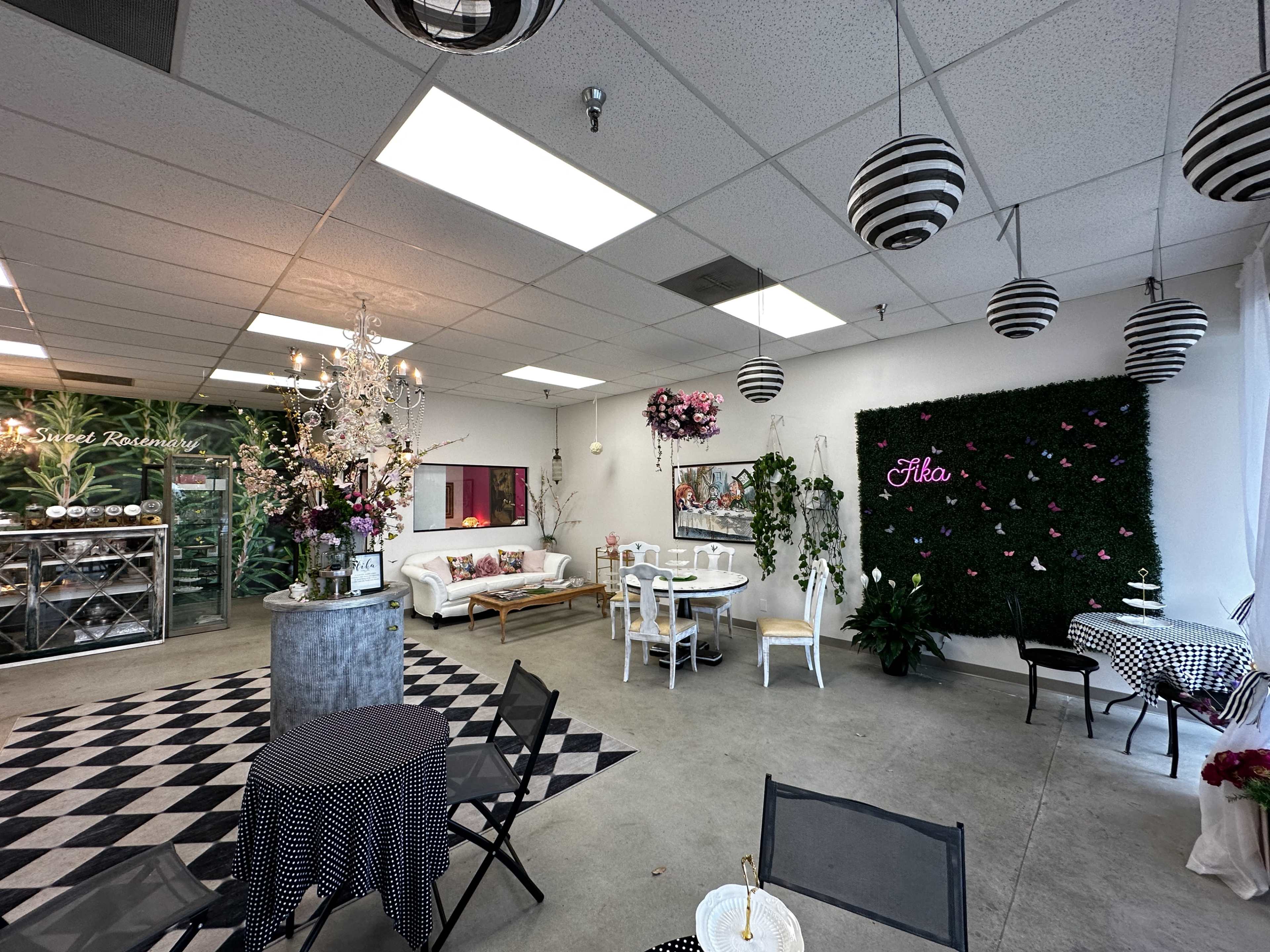 A spacious, decorated interior with seating arrangements, greenery, and decorative elements like a chandelier and wall art.