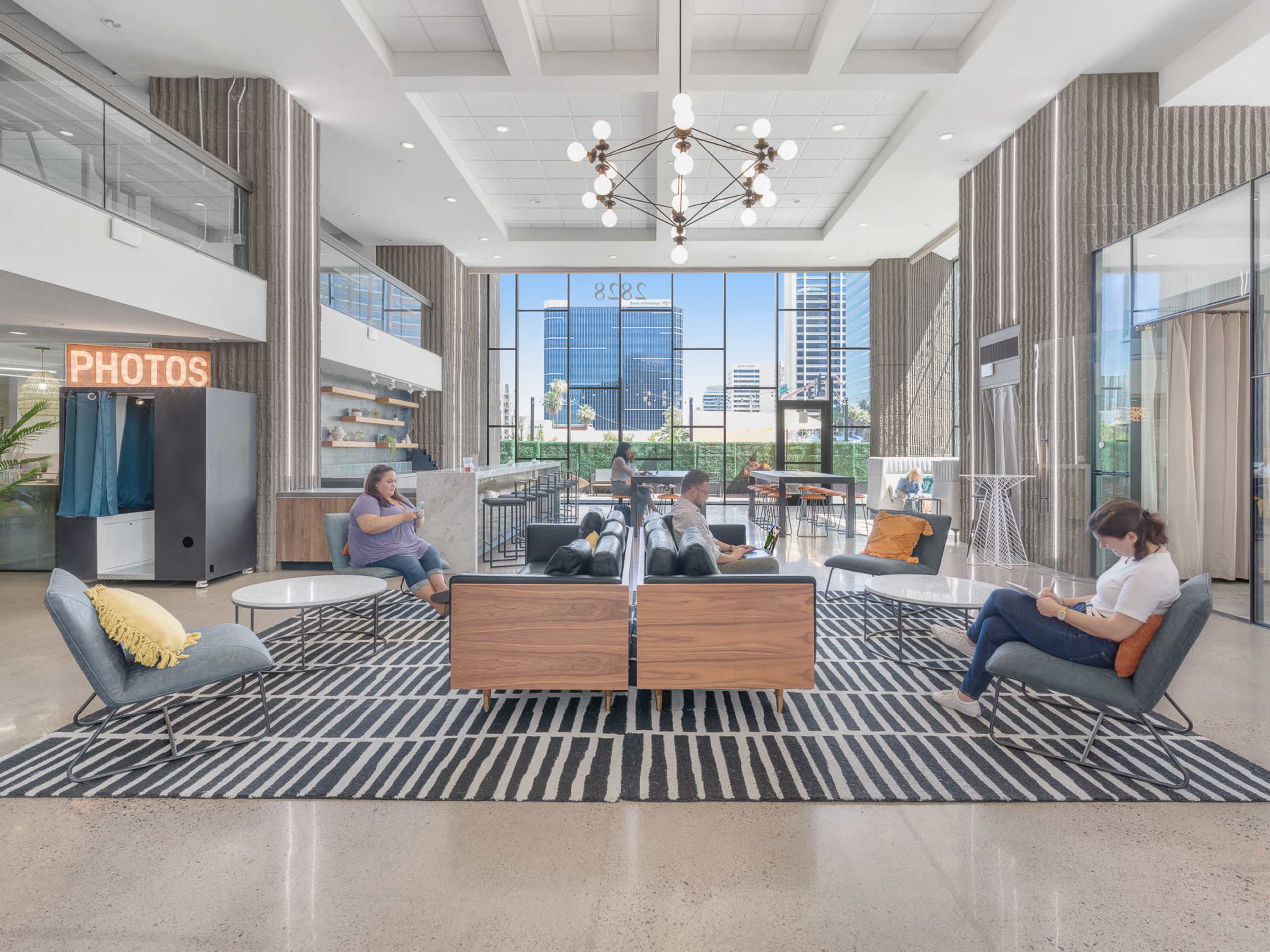 A modern lobby area with seating, a large chandelier, and natural light coming through large windows.