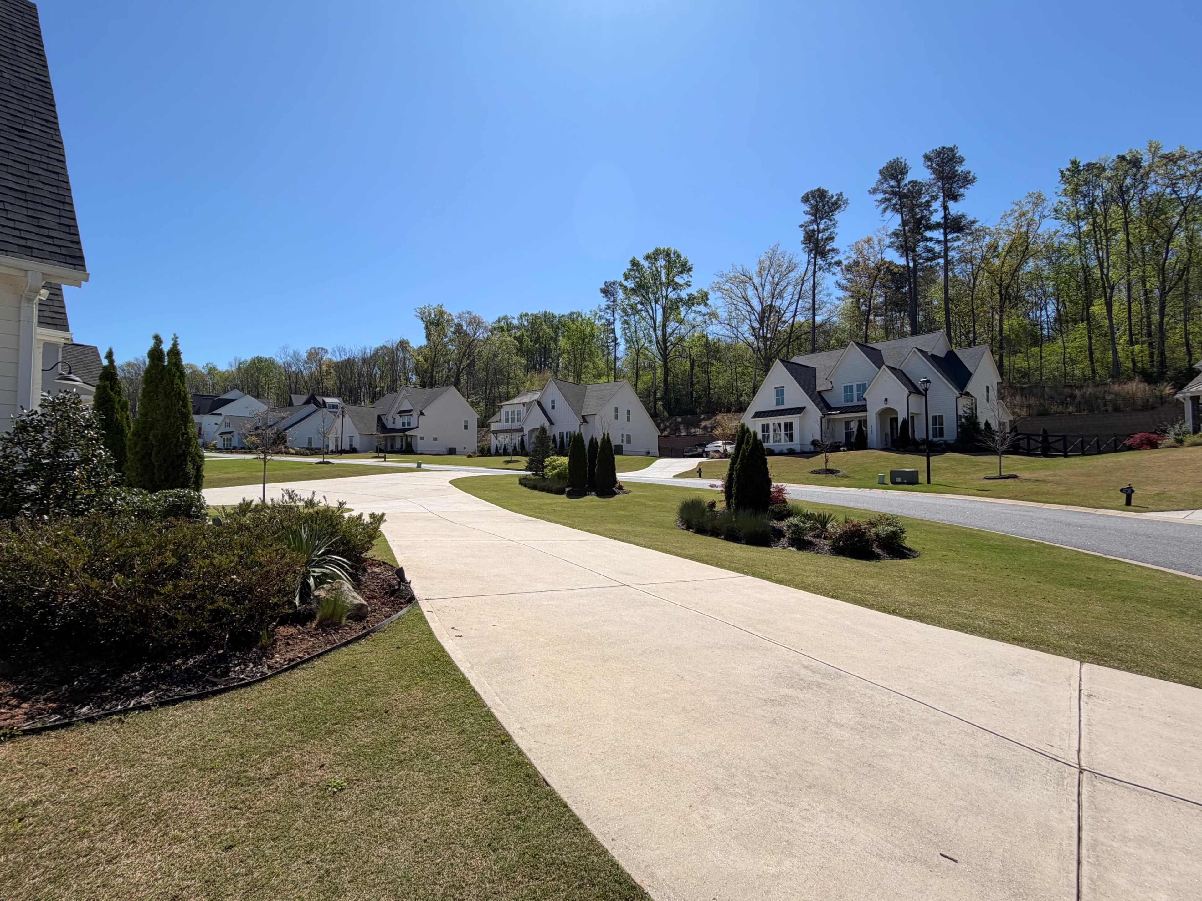 The image shows a suburban neighborhood with multiple houses lined along a curved driveway and greenery in the foreground.