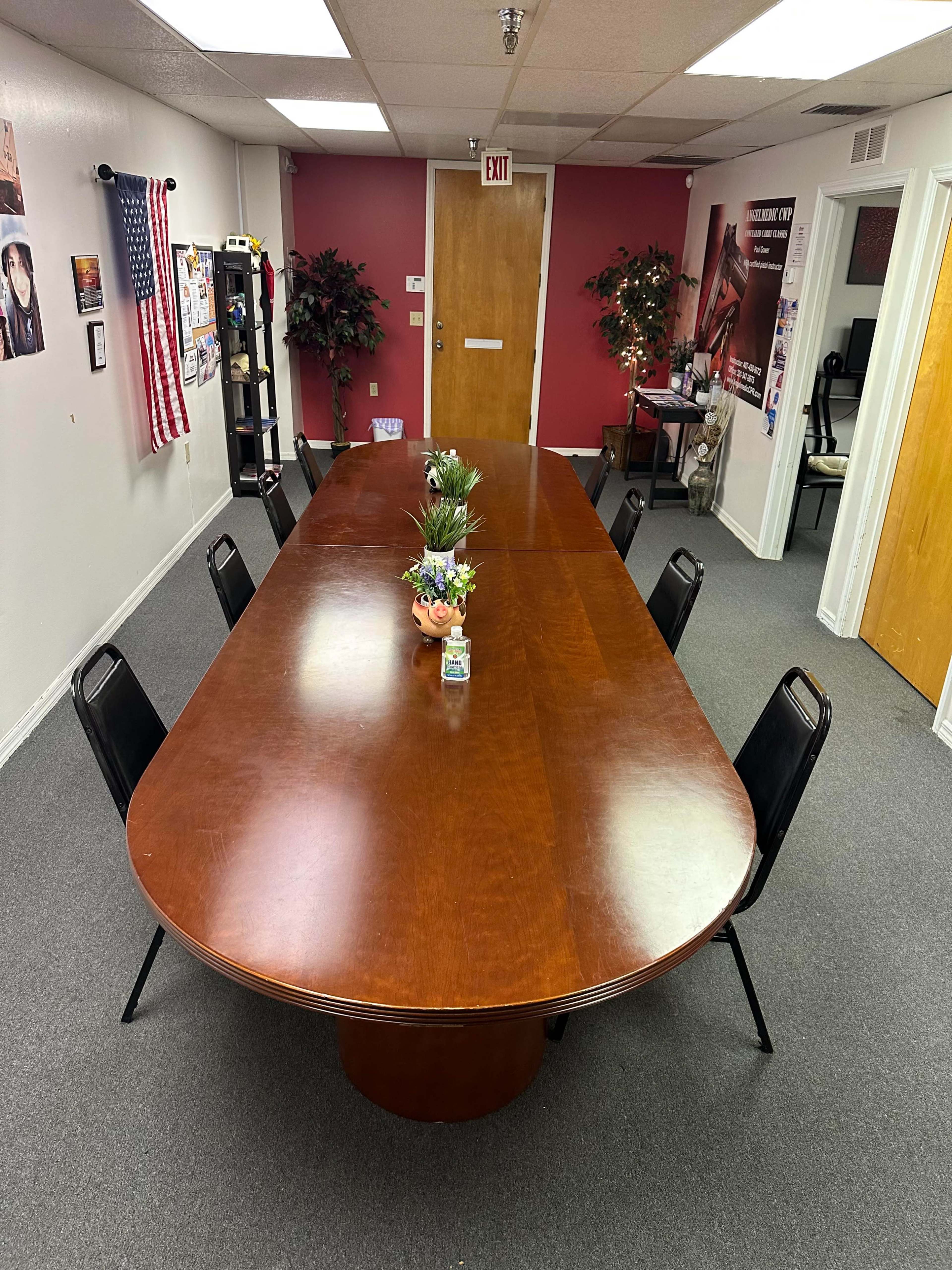 A large oval conference table surrounded by black chairs in a room with red walls and various decorations.