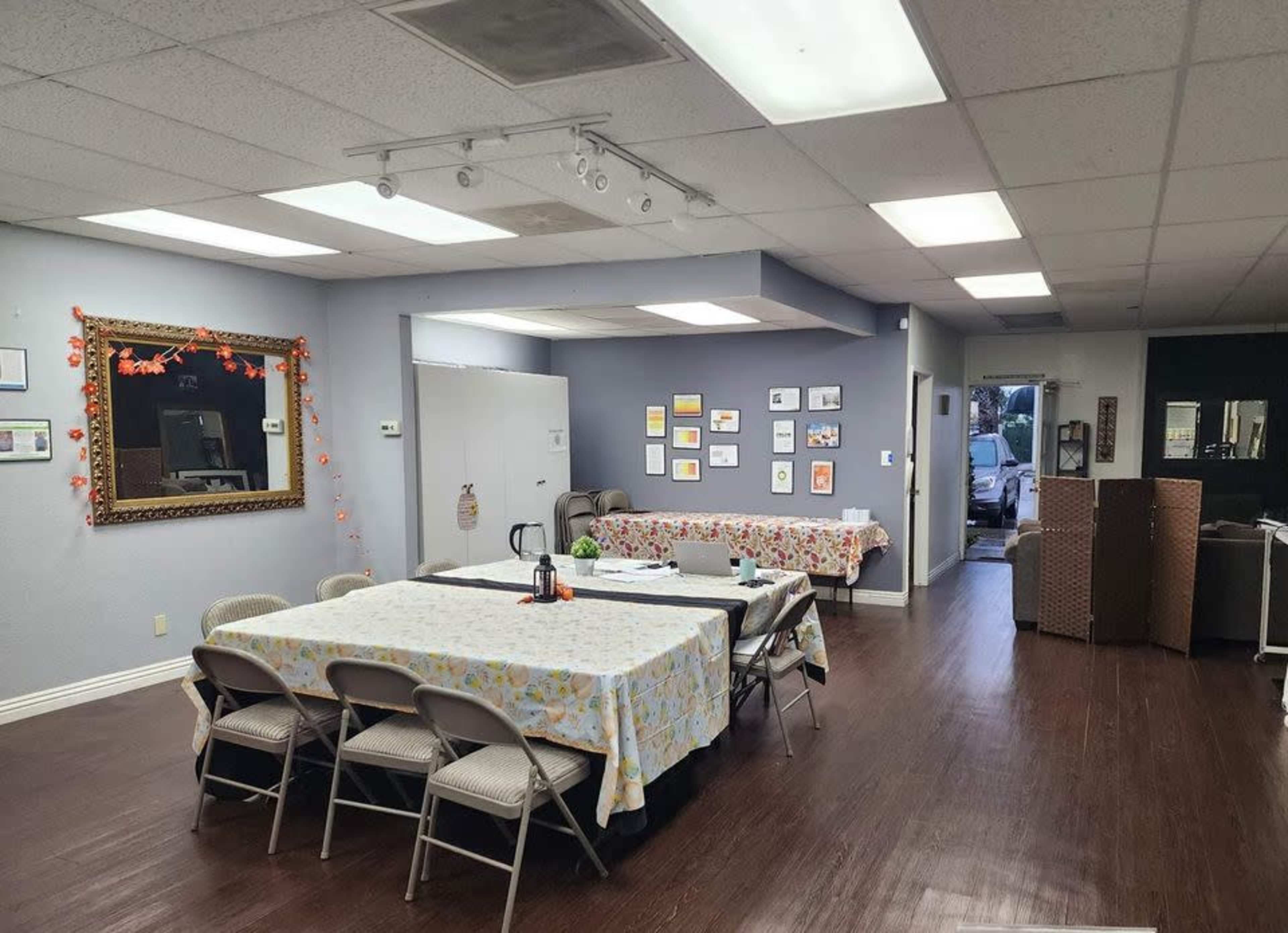 A spacious room with tables covered in cloths, framed artwork on the walls, and packing boxes stacked in one corner.