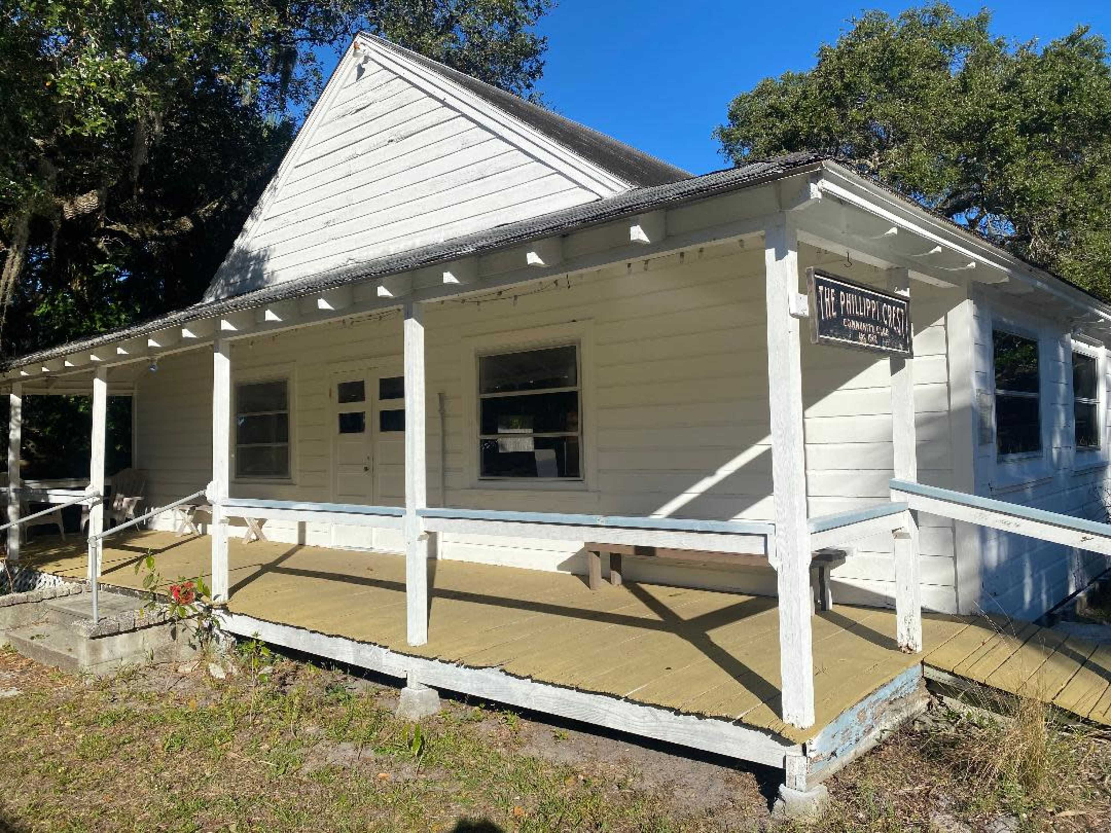 The image shows a white, wooden house with a front porch and a sign that reads "The Phillips House."