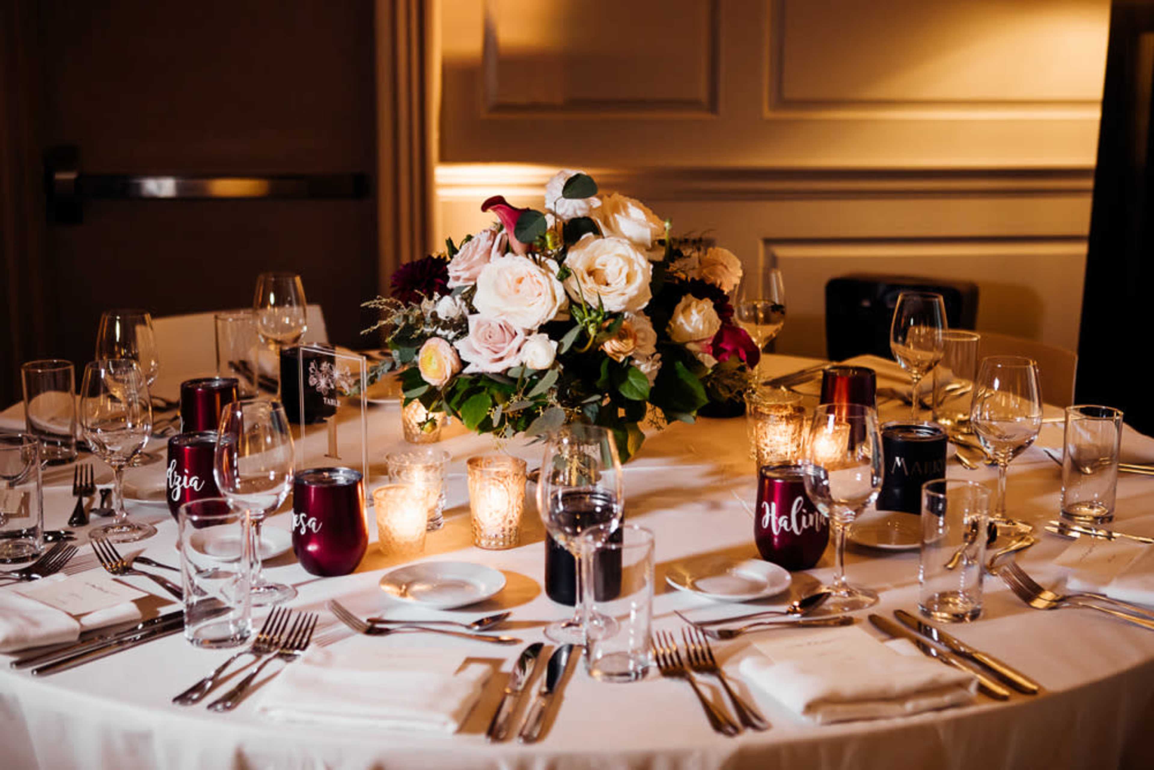 A elegantly arranged dining table features a floral centerpiece and various glassware set for a formal meal.