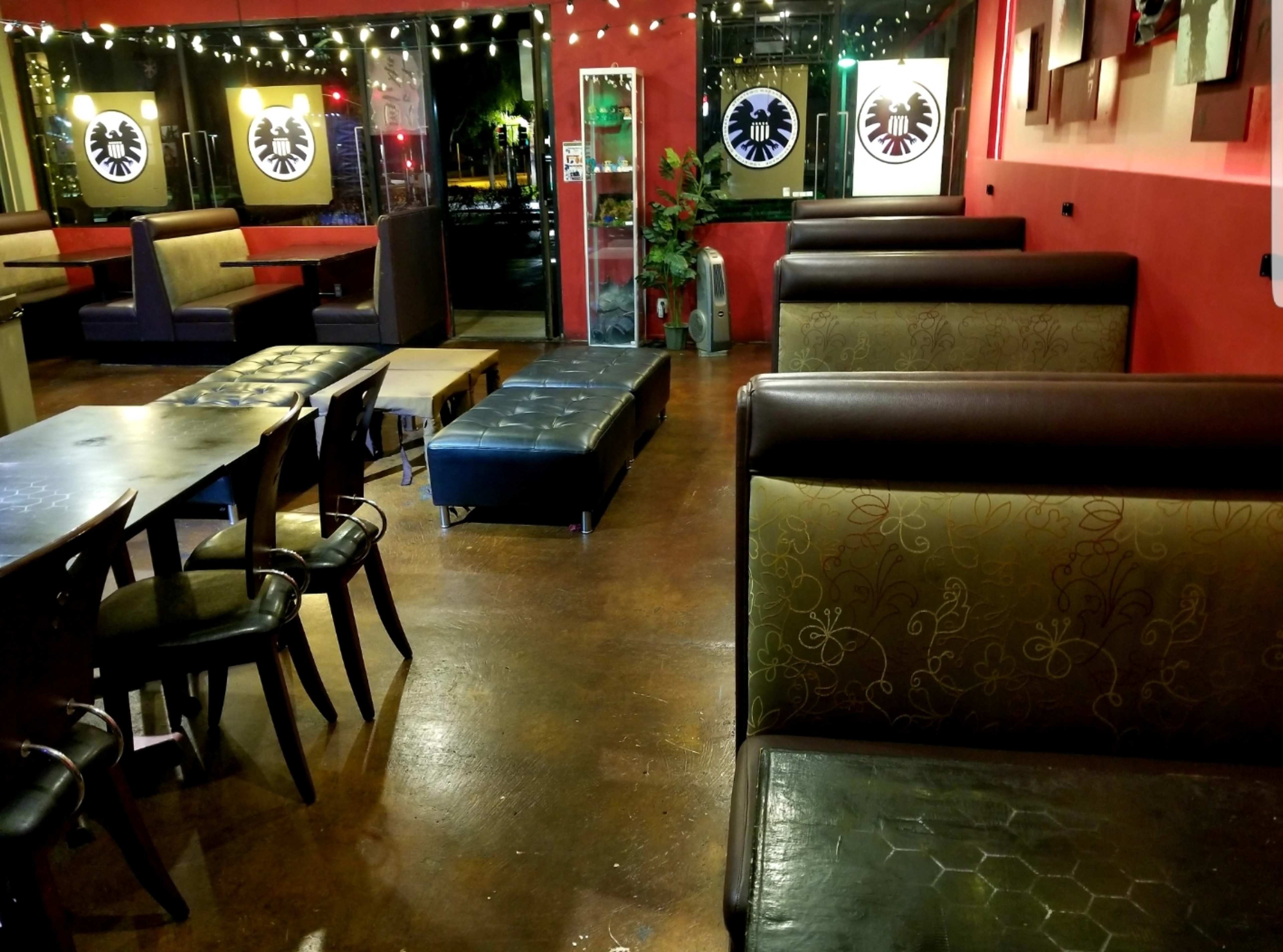 The image displays an empty restaurant interior featuring dark wooden tables and booths with decorative wall art.