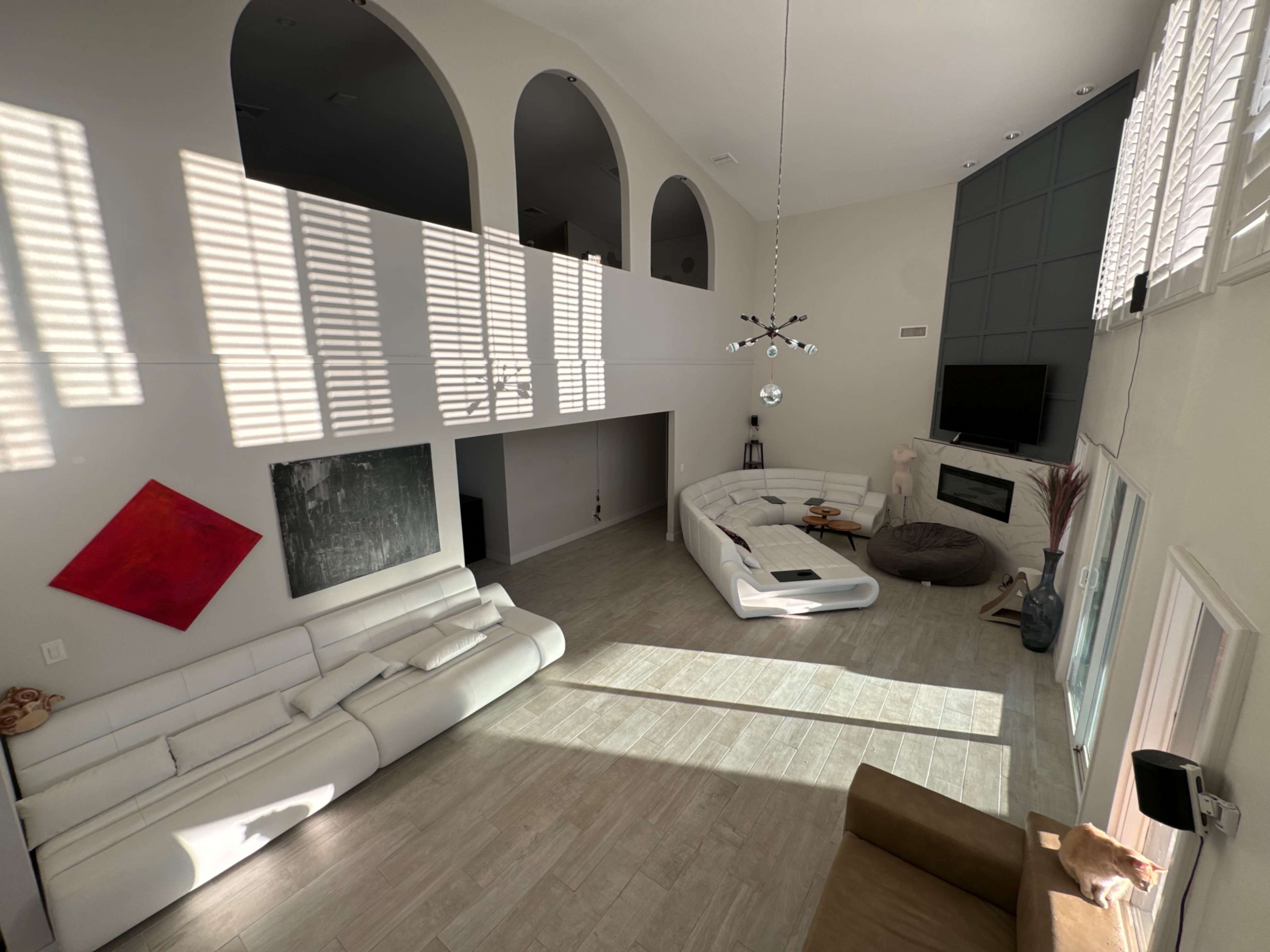 A spacious living room with modern furniture, large windows, and distinct architectural features such as arches and a fireplace.