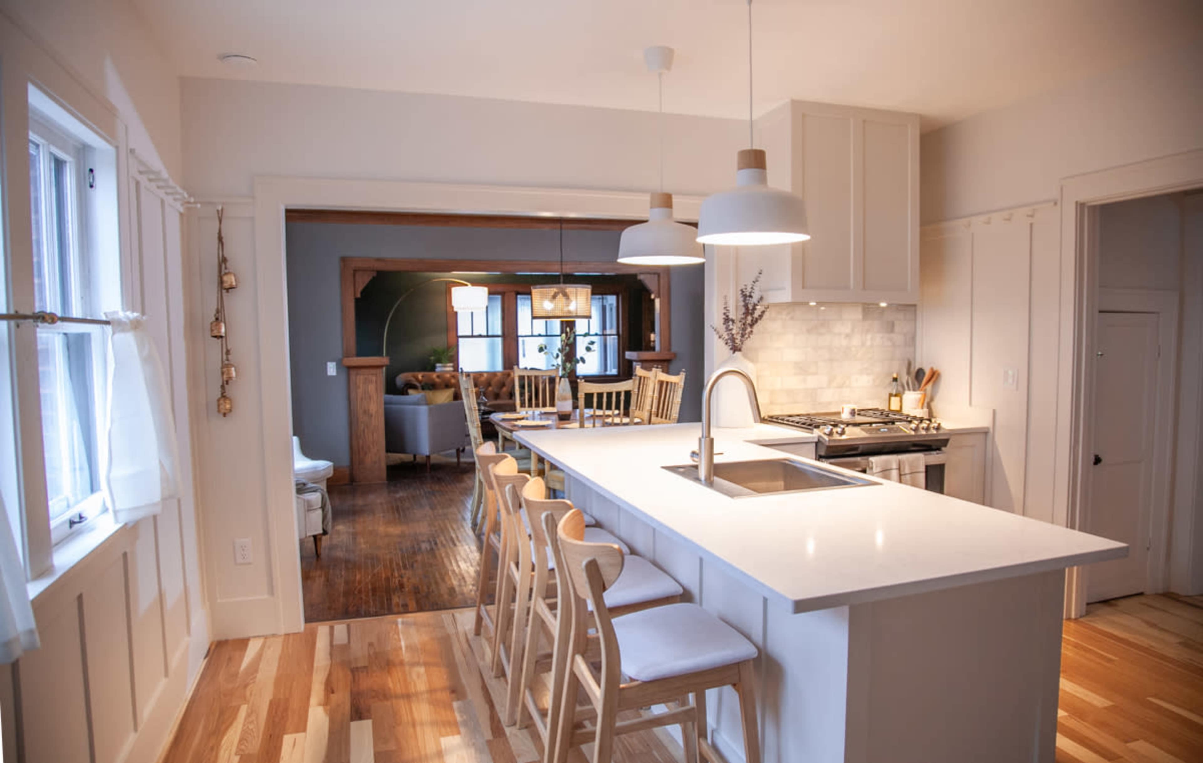 A modern kitchen features a central island with seating and a view into a cozy living area beyond.
