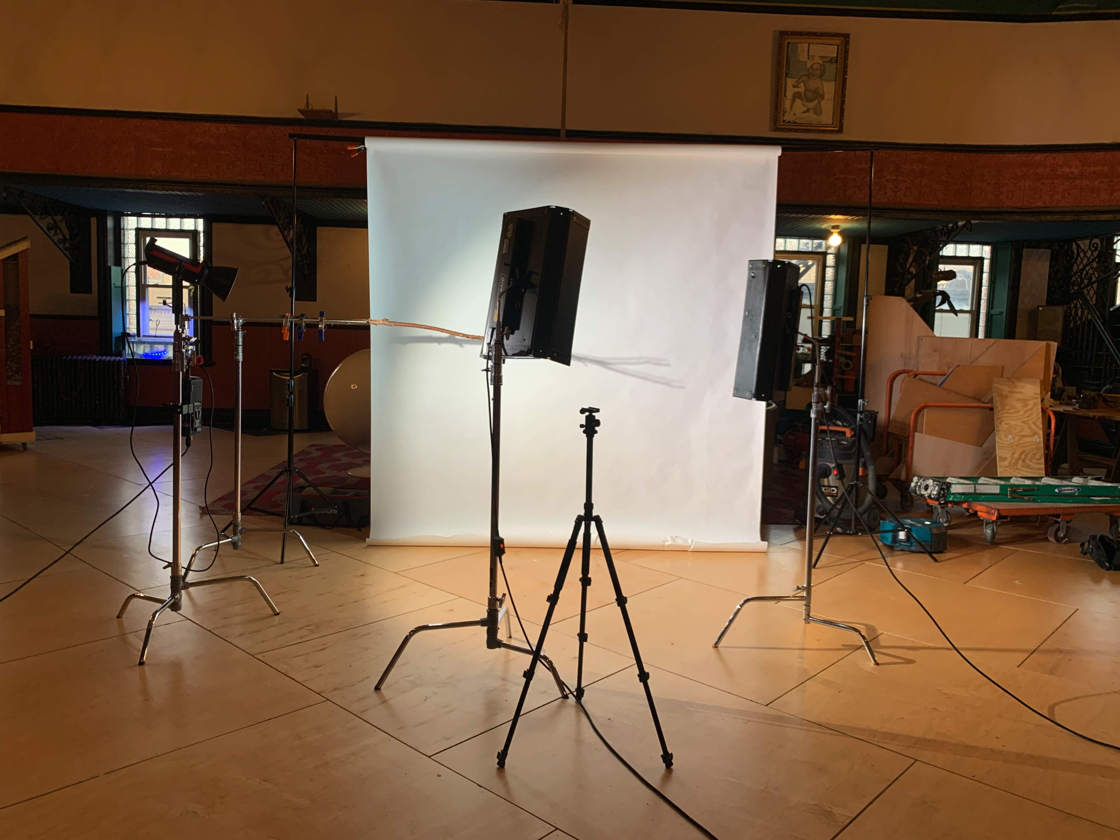 A photography setup is arranged with lights and a backdrop in a studio space.
